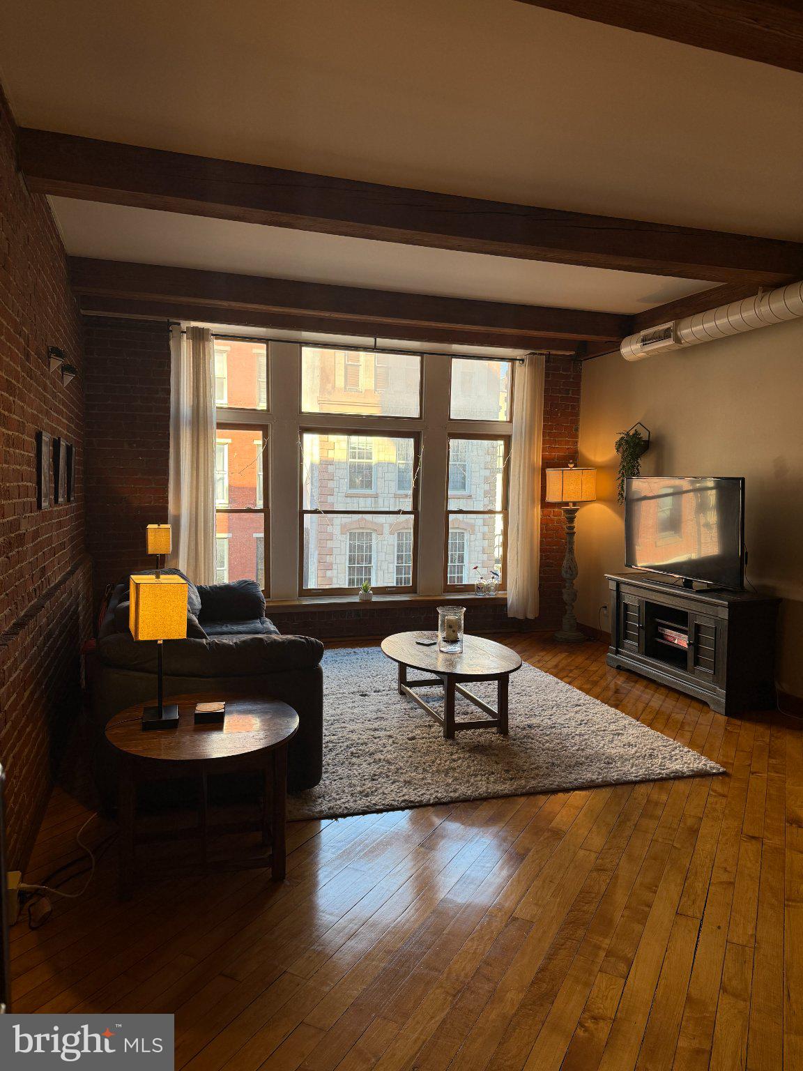 Picture yourself curled up on the couch, watching this winter’s first snowfall drift past these stunning oversized windows onto the cobblestone street below. This spacious one-bedroom loft sits in the true heart of Old City, just a block from Penn’s Landing and surrounded by countless restaurants, cafés and culture. Loft character is everywhere: soaring timber-beamed ceilings, warm exposed brick, and oak floors laid diagonally through the open living area. The floor-to-ceiling windows look original but are solid wood, double-pane, historically certified replacements, framing the beautiful architecture and cobblestones-with glimpses of the Ben Franklin Bridge.The bedroom is a fully enclosed and set in the quiet interior. It easily fits a king-size bed with plenty of room around it. It features an exposed brick accent wall and a walk-in closet with custom storage.  The galley kitchen offers Shaker-style wood cabinetry, stone countertops and a wide pass-through to the gorgeous living room.Whether you’re looking for a full-time residence or a stylish pied-à-terre, the location is hard to beat. Spend winter evenings at the Blue Cross RiverRink and summer nights at Spruce Street Harbor Park, or stroll to Independence Hall, the Liberty Bell, the Museum of the American Revolution, and Elfreth’s Alley. Restaurants, cafés, galleries, and boutiques line the surrounding blocks, and Old City’s First Fridays bring open galleries and lively streets right to your doorstep each month. The 2nd Street El station is just around the corner. This elevator building does not include parking, but a parking garage is just steps away.This is more than just a home; it's a lifestyle of sophistication and convenience waiting for you to embrace. Don't miss your chance to make this exclusive retreat your own!
