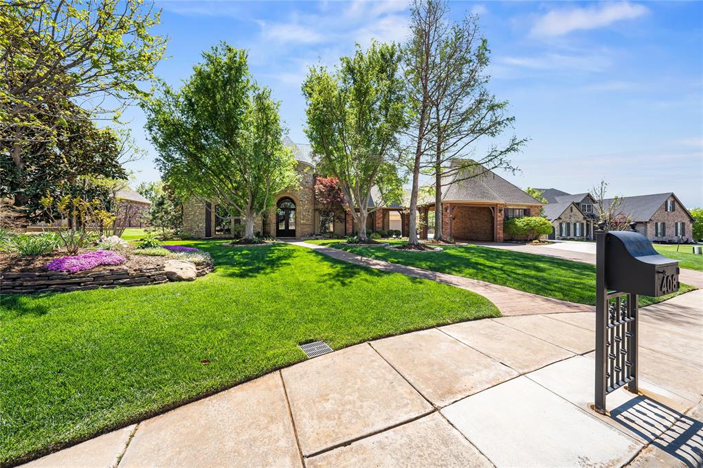 Perfectly positioned along the 13th tee box on the East side of Oak Tree Golf & Country Club, this exceptional estate delivers a true resort-style living experience with breathtaking golf course views and refined luxury throughout. From the moment you arrive, the impressive 24-foot grand entry sets the tone for elegance and sophistication. Inside, hand-scraped hardwood floors lead you into an expansive living room featuring soaring vaulted ceilings and floor-to-ceiling stacked stone fireplace. Walls of windows frame views of the pool, outdoor living spaces, and pristine fairway beyond, creating a seamless indoor-outdoor connection. The chef’s kitchen is thoughtfully designed with high-end finishes, including a Sub-Zero refrigerator, six-burner gas cooktop, center island, pantry, and a spacious dining area, making it ideal for both everyday living and entertaining. The luxurious primary suite offers a private retreat with a beautifully remodeled spa-inspired bathroom featuring a soaking tub, expansive walk-in shower, dual vanities, and a custom walk-in closet. A distinguished study with its own fireplace and custom built-ins provides an elegant workspace, while the formal dining area is complemented by a stylish wet bar. Upstairs, a private ensuite bedroom features a remodeled bathroom, while the expansive bonus room is designed for entertainment, complete with a beverage station, and access to a fully equipped home theater with seating. Outdoor living is equally impressive, featuring a resort-style pool with stone water feature and spa, outdoor fireplace, and built-in grill, all perfectly positioned to enjoy the serene golf course backdrop. Additional highlights include secondary bedrooms with walk-in closets, a utility room with built-ins and laundry chute, storm shelter in the garage, a new pool heater, and a new roof (2024). This extraordinary property offers a rare opportunity to experience luxury, privacy, and golf course living at its finest. Welcome Home!