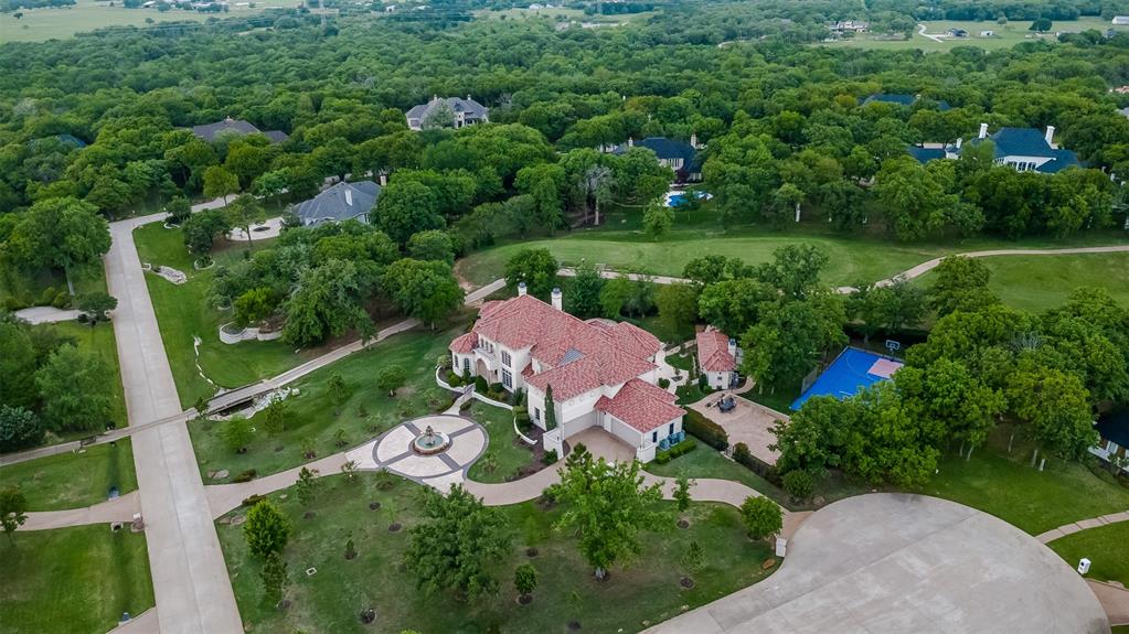A stunning golf course estate designed for those who love to entertain and live exceptionally well, this 7,499 square foot residence sits on 1.82 acres in a cul-de-sac on the golf course within the prestigious Estates at Tour 18, a 24-7 guarded and gated community. From the moment you step inside, soaring 25-foot ceilings create a dramatic and inviting presence, setting the tone for a home that is both grand and welcoming. Designed for hosting on any scale, the home features a dedicated media room, an large game room with kitchenette, and seamless indoor-outdoor living. The resort-style backyard offers a sports court, pool, and an impressive gas firepit, making it the perfect setting for unforgettable gatherings. At the heart of the home, the oversized kitchen is as functional as it is beautiful, featuring dual dishwashers, a vegetable sink, and striking lighted Cristallo countertops. Around the corner, a built-in desk area provides space for homework or everyday organization. The secluded master suite is a true retreat, complete with a sitting area. A versatile bonus room with a closet, ideal for a nursery, private office, craft room, or additional storage is nearby. The spa-like master bath offers a steam shower, rain head, and a towel warmer for a true luxury experience. Three additional bedrooms are upstairs, including one with its own balcony. A separate guest house offers comfort for extended stays or multigenerational living. Every detail has been carefully chosen, from marble countertops in all bathrooms to a central vac system, electronic window treatments, and chandeliers that lower electronically for easy maintenance. Set within one of the area’s most sought-after gated communities with scenic golf course views, this home offers a rare combination of privacy, scale, and elevated living. You can keep searching… but you won’t find another one like this. Many furnishings in the home are available for purchase. Seller holds a TX real estate broker license.