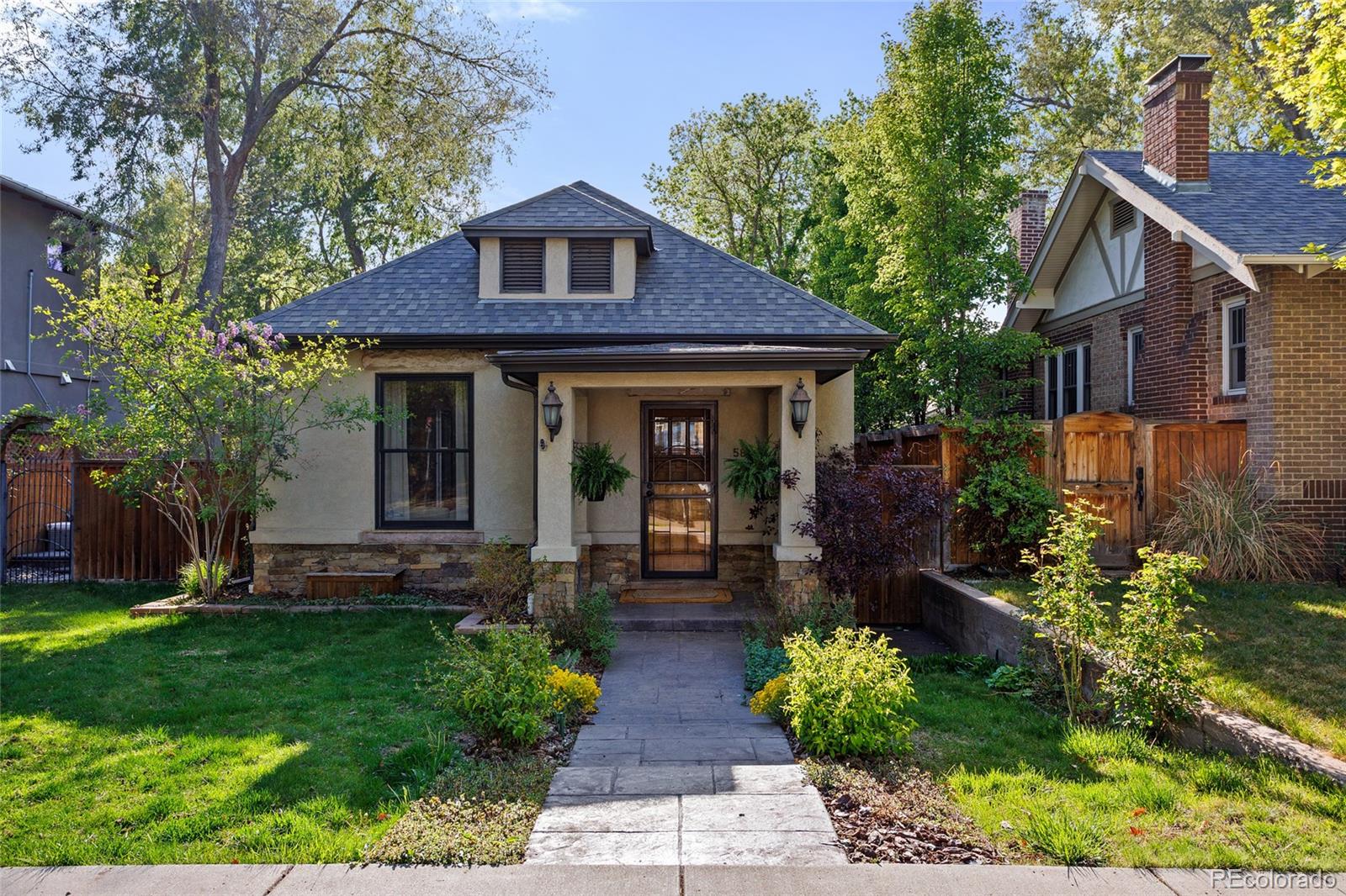 West Wash Park Historic Modern Bungalow situated on a tree-lined street just three blocks from Denver's iconic Wash Park. Curb appeal defined by a low-slung roofline with dormer, Craftsman-style columns anchored by stone bases and a warm stucco exterior with black trim—setting the tone before you step inside. A thoughtful renovation & expansion keeps the soul of the original home while delivering a rarely found open floor plan, elevated ceiling heights and a true garden-level lower floor with oversized windows and natural light. A seamless connection from the open floor plan to a south-facing side patio and lawn pulls natural light in throughout the entire home. Living room is anchored by the original fireplace—refined and converted to gas. Kitchen hits the balance of elevated and functional: granite countertops, Bosch appliances, warm cabinetry and island with bar seating. Glass doors fully open the kitchen and dining spaces to the patio, creating a true indoor/outdoor flow. Wide-plank, 4-inch white oak flooring runs throughout the main and upper levels—clean, continuous and modern. Magazine-worthy powder bathroom on the main level—perfect for entertaining guests. The rear addition is where the home opens up—split tri-level design adds dimension: half-flight up leads to a bright lofted office and lounge before entering a spacious primary suite with a renovated 5-piece bath, dual vanity, walk-in closet and a private west-facing deck. Half-flight down offers three true bedrooms, a 3/4 bath, dedicated laundry and a large storage space. Outdoor living fully dialed in with the private side patio and natural gas hookup, plus a fully fenced, south to west wraparound lawn. Large two-car garage plus two rare off-street parking spaces—hard to come by in this location. Positioned among the best of West Wash Park, S Broadway and S Gaylord Street—walkable to coffee, restaurants, boutiques and neighborhood spots. Quick access to S Pearl Street, Cherry Creek and Downtown.