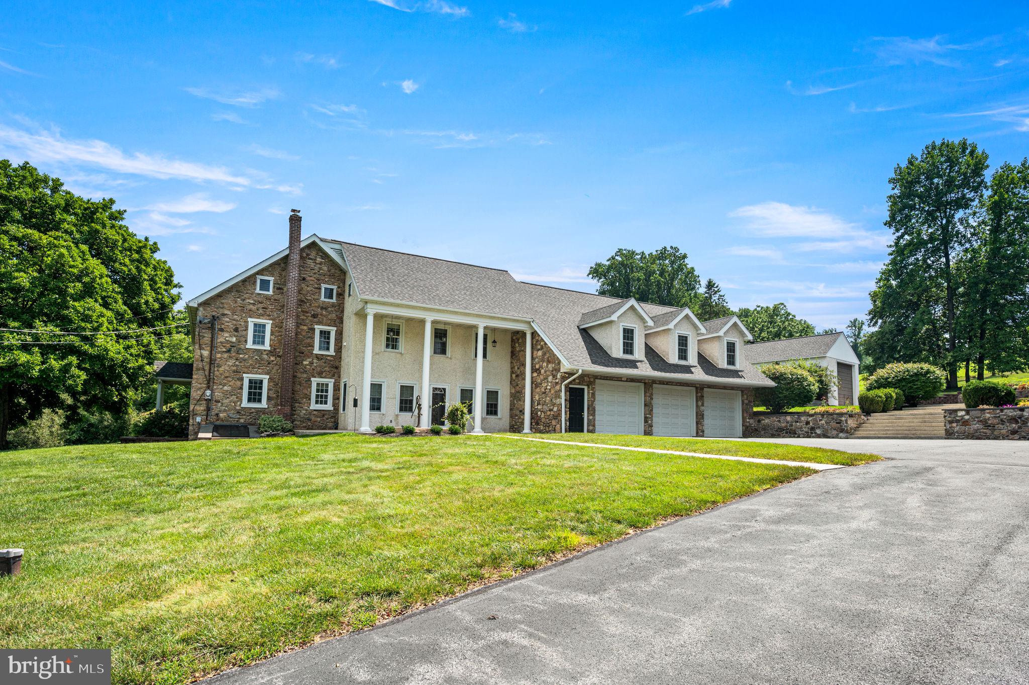 Situated on about 13 scenic acres in the rolling hills just outside of Boyertown, this almost 5000 square foot impressive and expanded stone farmhouse is the ideal homestead for active lifestyles.  Whether you are a car collector, hobbyist, contractor, or gentleman farmer, the huge bank barn, multiple outbuildings, and many garages will give you plenty of space to pursue your ambitions.  The sprawling and updated home, with its beautiful in-ground pool, expansive patios and porches, is perfect for indoor and outdoor entertaining on a grand scale.  Greet guests on an impressive two-story portico. The welcoming floor plan features a huge 40-foot long great room with giant raised hearth stone fireplace, live edge custom bar and cabinetry, bay window, and hardwood flooring. The remodeled kitchen includes quartz counters, tile backsplash, wood floors, double oven, range top alcove, brickwork, a butcher block topped island, and an adjoining breakfast room. A den, entrance hallway, and convenient marble powder room are also located on the ground level. The large second floor is accessed by the home’s original turned staircase, as well as by a stylish modern hardwood curved staircase with wrought iron railing.  This level includes a primary bedroom and en-suite bathroom with walk-in shower, soaking tub, 8’ double vanity, custom tilework; three additional bedrooms; a second full hall bathroom; plus an additional suite of rooms on the back wing to the home.  This bonus suite with two spacious rooms separated by French doors, walk-in dormers, extensive storage, and a powder room could serve as a great home office, guest suite, or recreational activity space. Convenient access to this extra living space can be found via a staircase from the garage, direct access to the second floor, as well as an exterior door leading to the back parking lot.  There is plenty of storage space throughout the home including a walk-up attic and large basement with interior and two exterior entrances.  Parquet wood floors, hardwood flooring, exposed stone interior walls, custom tilework, deep windowsills, and many vintage and historic components add great charm throughout the home.  There is plenty of outdoor space to host large gatherings in the beautiful, partially covered 33’x35’ courtyard framed by flagstone-capped stone retaining walls with built-in bench seating. This area features a unique pebble-finish concrete patio, stone pillars, and barn doors opening to the 3 car garage.  A stone archway leads to the picturesque pool area surrounded by an expansive patio.  The large in-ground pool was just re-plastered and had new coping and tile installed by Anthony and Sylvan pools in July of 2026.  If you are looking for significant storage and workspace for your business or interests, this property has you covered: there’s a 67’x35’ two level, bank barn with two garages on each level. This structure is in great shape and has undergone major renovations.  Other outbuildings include an oversized 39’x19’ garage with a 12’x12’ overhead door; a separate 30’x15’ garage, and charming stone springhouse with water race.  Two large parking lots will accommodate many vehicles. For potential business owners, the township has approved the operation of an owner-occupant’s trade business at this location.  Properties with this combination of beautiful acreage, quality construction, close to 5000 SF of finished living space, extensive custom outdoor hardscaping and entertaining space, and an assemblage of impressive outbuildings are rarely on the market.  Be sure to visit 112 Terrace Road and see all that this spectacular homestead has to offer.