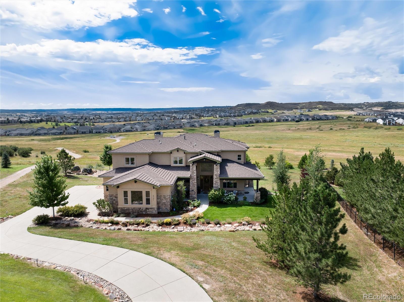 Welcome to this exquisite 6-bedroom, 7-bath custom home nestled in the highly sought-after Pradera Country Club. Perfectly positioned on over an acre and backing to open space, this home captures breathtaking views and offers the ultimate in privacy, luxury, and functionality. Step into a grand entrance that sets the tone for the quality craftsmanship found throughout. The stunning chef’s kitchen features Sub-Zero and Wolf appliances, a spacious island, and a walk-in butler’s pantry—perfect for entertaining. The adjoining family room boasts vaulted ceilings and a showstopping fireplace, flowing seamlessly to a large covered deck overlooking scenic open space. Enjoy formal dining and living rooms ideal for hosting guests, and a versatile main-floor bedroom with a private entry to the deck, perfect for a home office or guest suite. Upstairs, the luxurious primary suite offers a cozy fireplace, sitting area, and built-in coffee bar. The spa-like primary bath features radiant heated floors, a soaking tub, dual-head steam shower, and a walk-in closet with direct access to the laundry room. Each of the three secondary bedrooms upstairs includes its own en-suite bathroom for ultimate comfort and privacy.  The recently finished basement is an entertainer’s dream, complete with a full bar featuring a refrigerator and dishwasher, a spacious rec area with a stylish half bath, an additional master suite with a marble tiled en-suite full bathroom, a massive storage area closet with custom shelving. Relax in the private hot tub while soaking in panoramic views. With dual furnaces, two A/C units, an industrial-grade water heater, and a state-of-the-art PURONICS water system, this home delivers year-round comfort and efficiency. All of this, set on a beautifully landscaped 1+ acre lot in a premier golf community.*SELLER WILL PAY GOLF INITIATION FEE AND UP TO $2,500 FOR MONTHLY DUES DIRECTLY TO THE CLUBHOUSE ON BEHALF OF THE BUYER - With a full price offer*
