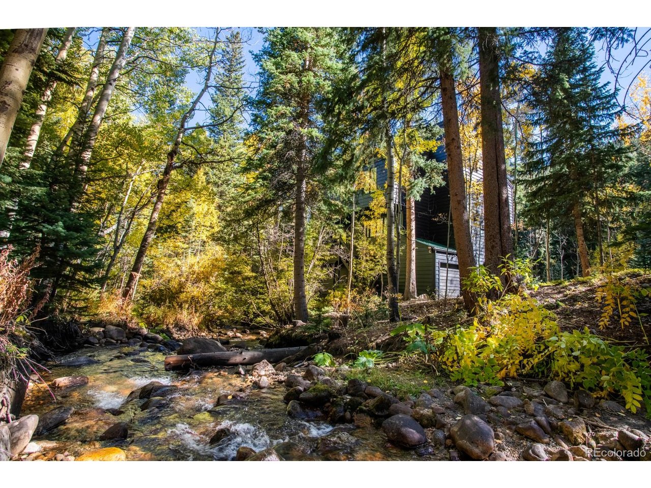 Nestled in the forest near Idaho Springs this home offers a serene setting backing to Mill Creek. Just imagine enjoying your coffee from your expansive back patio while listening to the creek flow past... If "forest bathing" is your perfect type of mental & physical wellness this home will not disappoint you. There is a pergola-covered deck w/ a porch swing & so many places for a hammock that create ideal spaces for entertaining or relaxing. Inside, the updated kitchen is both functional & inviting w/ quartz countertops, new fixtures & lighting, double oven, dishwasher, & SS refrigerator.  There is ample room at the counter for entertaining & a large dining area for your get-togethers. The bonus room would make a great office or potential for 3rd bedroom w/ built in seating, storage & an updated half bathroom.  The living room is a showstopper with soaring T&G ceilings and 2 stories of floor to ceiling windows.  Updated LVP flooring, storage  and a gorgeous wood burning fireplace.  The living room opens to the back deck that spans the back of the house and overlooks Mill Creek. Upstairs, the spacious primary suite is large and open with vaulted ceilings, a private patio to enjoy the forest and creek, and a luxurious bath with vaulted ceilings, a soaking tub framed by floor-to-ceiling windows, glass shower and a dry sauna. An additional large bedroom, full bath, laundry room, and a large loft with vaulted ceilings-ideal for a studio, yoga space, or observatory-complete the upper level.The walk-out lower level features a cozy den with a wood-burning stove, backyard access, generous storage, and entry from the garage.Surrounded by walking trails and located just 40 minutes to Golden and 45 minutes to world-class skiing at Winter Park or Copper Mountain, this home offers the perfect balance of tranquility and adventure. Just minutes from the new Idaho Springs Gondola which is part of the Virginia Canyon Mountain Bike Park.  Long term and short term rentals allo...