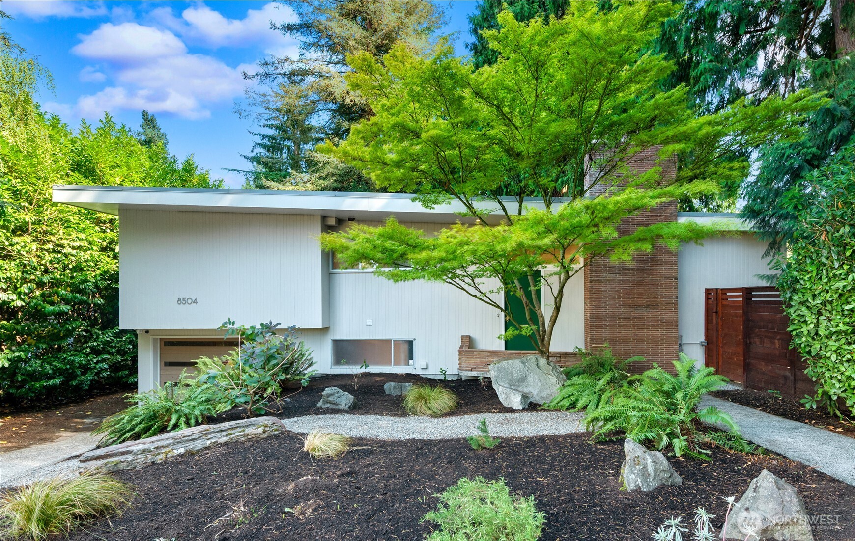 A rare opportunity to own a piece of Seattle architectural history in the heart of Wedgwood. Designed in 1948 by celebrated Seattle architects James J. Chiarelli and Paul Hayden Kirk, this distinctive Northwest Modern stunner was originally conceived as a Revere Model Home showcasing innovative postwar design with an emphasis on quality craftsmanship, natural materials and seamless indoor-outdoor living. Set on an oversized, private corner lot surrounded by mature landscaping, the home still captures the vision that made it special more than 75 years ago. Walls of glass invite abundant natural light and frame the lush surroundings, while warm wood details, clean architectural lines and fantastic mid-century character establish a feeling that is timeless and wonderfully unique. A custom designed kitchen completed in 2021 brings modern functionality while complementing the original aesthetic. Generous living spaces connect effortlessly to the outdoors, creating a private retreat in one of NE Seattle’s most beloved neighborhoods. Architecturally significant, beautifully preserved and undeniably cool this is quintessential Pacific Northwest modernism in Wedgwood.