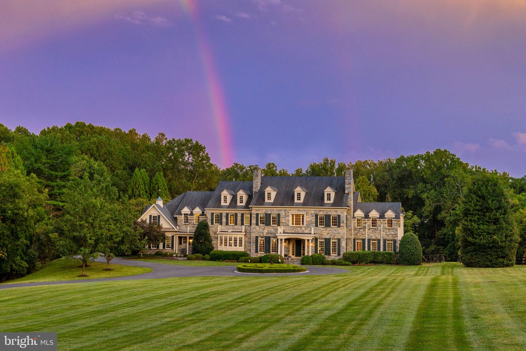 First time offered for sale, this exceptional 5-acre estate is nestled at the end of a private road surrounded by lush gardens and mature trees. The custom designed field stone manor home boasts timeless elegance and offers over 12,000 Sq ft of living space.   A circular drive framed by boxwoods leads you to the grand portico. Entering the home, grandeur unfolds with soaring 12’ ceilings, luxurious cornice moldings, wide plank floors and a towering 2 story wall of windows looking out to the verdant backyard.  The two-story foyer with double curved staircase and in-laid rosewood compass medallion in the center are breathtaking. The main level features elegant formal rooms grand in scale and include a living room and dining room with period fireplace mantels and antique lighting. Unique features include a butler’s pantry hidden behind pocket doors, custom designed pine library, extra wide hallways, a separate guest coat closet, formal powder room and light-filled conservatory with double doors opening to the porch. The kitchen boasts Sub-Zero, Viking Professional, and Thermador appliances as well as custom cabinetry and a large island with warming oven.  A sunken family room flows off the kitchen with custom built-ins, floor to ceiling stone fireplace with gas logs and large windows bringing in lots of light. A morning room is off to the side withdouble doors leading to the backyard terrace and fountain. The first floor includes a pantry, catering kitchen with additional Sub Zero, mudroom with cubbies, half bath and sports closet. Two separate staircases lead to the upper level where 5 spacious bedrooms with en-suite bathrooms can be found. Arches mark the hallways to each end of the house. The laundry room has linen closets on each side of the entry door, built in cabinets and shelves for folded laundry. A children’s library with built-in bookshelves and window seats for storage can be found at the end of one hallway while the master suite sits at the other end. A circular entry foyer with inlaid wood medallion leads to the master bedroom where a sitting room with gas fireplace, cofferedceiling, 2 expansive walk-in closets and separate cedar-lined closet await. The bath is adorned with Carrera marble, dual vanities, whirlpool tub beneath a Palladian window and walk-in marble shower. The lower level includes a sports game area designed for 3 TVs to keep up with games or play X-Box; custom bar area, billiards room, sitting area with fireplace, exercise room, half bath, au pair suite with en-suite bathroom and 2 storage closets. A professionally designed and installed home theater features Klipsch surround sound and leather seats. A custom-designed wine cellar accommodating over 800 bottles features a built-in humidor. The outdoor patio with towering stone fireplace, built-in gas grill and bar are designed for year round enjoyment and ideal for gatherings under the stars. Formal gardens with boxwood hedges and fountain set the stage. A 50’ x 20’ heated pool with retractable cover and hot tub are hidden off to the left. Stone pillars with an antique gate frame the exit from the pool area to he rest of the property. There is room for tennis/pickleball courts or for a barn and riding ring. The garage has 2/3 parking spots including a double bay for a large SUV. A parking area outside the garage accommodates additional cars.  This property boasts 4-zone HVAC, updated water heater and water monitoring system, water purification system and pressure systems, whole-house CAT5 wiring and audio, and a 30-year Grand Manor roof.  The park-like grounds create a sense of seclusion despite being minutes from Tysons Corner,Dulles Airport and Beltway. This property offers a perfect balance of privacy, elegance and convenience giving a sense of tranquility that feels worlds away from the hectic pace of city life. 1205 Towlston Road is more than a home—it’s a legacy property designed for timeless living and grand entertaining.