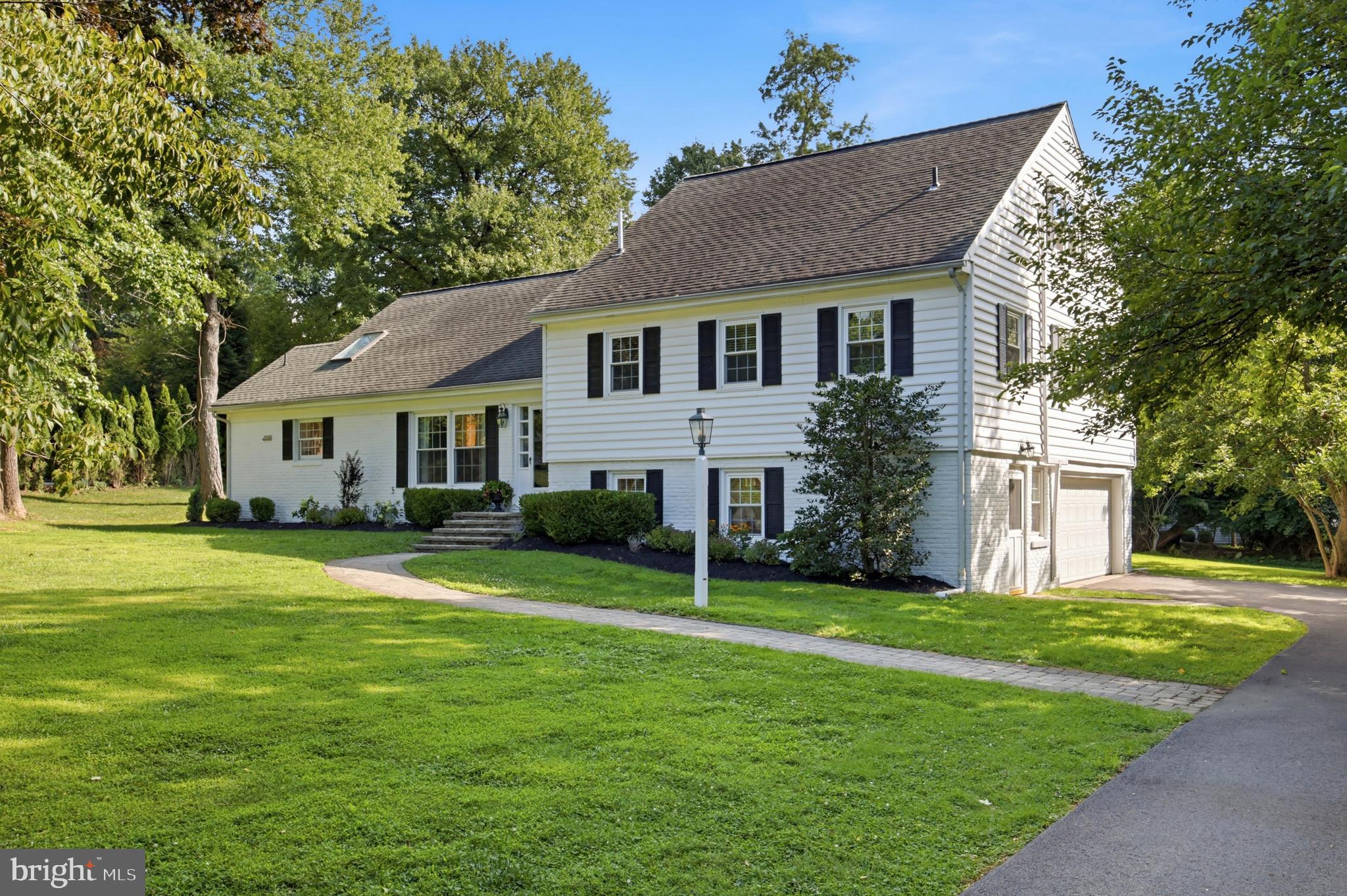 Welcome to this charming and deceptively spacious home, ideally situated on one of the most picturesque lots within a sought-after Devon neighborhood in the heart of the Main Line. Set on a large, level lot with beautifully maintained landscaping, this home offers a wonderful combination of character, space, natural light, and an exceptionally functional layout. Natural wood hardwood floors extend throughout the home, beginning in the welcoming foyer with a convenient coat closet. To the left, the intimate dining room features a long double window overlooking the spacious front yard and opens directly into the beautifully renovated kitchen, completed in 2020. The kitchen offers white marble countertops, stainless steel appliances, a gas range, double ovens, and a large natural wood island with additional storage and seating for 4–6.The front entry also leads naturally into the formal living room, where a wood-burning brick fireplace is framed by two built-in bookshelves. Three large windows overlook the flagstone patio, while double French doors open into the breakfast nook. This inviting space features a built-in long bench flanked by two built-in cabinets with rich natural wood tops. Above, an oversized bank of four windows fills the room with sunlight.The breakfast nook flows seamlessly into the expansive family room, creating a wonderful open connection between the kitchen, breakfast area, and main gathering space. With ceilings reaching approximately 15 feet, two full walls of floor-to-ceiling built-in bookshelves, and a tucked-away built-in office area, this room offers both impressive scale and everyday functionality. A full wall of windows, complete with a built-in bench and drawers below, brings in exceptional natural light while providing additional storage.Two large, door-sized windows and a French door open from the family room to the flagstone patio and private backyard, where a large playground area provides space for outdoor enjoyment.The lower level offers additional flexibility and functionality, with ample space for storage or a future mudroom, along with a separate laundry area, convenient half bathroom, tiled flooring, and built-in storage. This level also provides direct access to the garage, which leads to a large, dry crawl space offering excellent additional storage. A side entrance provides convenient access from the driveway directly into the lower level. The exceptionally long driveway was recently paved in 2025.The bedroom levels offer five bedrooms in total. The first upstairs level provides three generously sized bedrooms each feature closets, with one offering a private en-suite bathroom with shower. A second full hall bathroom includes a tub and shower, along with a convenient linen closet. The next level features another spacious bedroom with ample closet space, including two deep sliding closets with lower built-ins and a separate walk-in closet. A skylight brings in natural light, while the room opens to a private full bathroom with vanity, tub, and shower. Additional unfinished storage space is also accessible from this level. The fifth bedroom is exceptionally spacious and offers two large closet spaces that could easily serve as study, reading, or work-from-home nooks, along with two additional closets and access to attic storage. Another skylight adds natural light to the room.  With its level lot, established landscaping, abundant windows, hardwood floors, extensive built-in storage, flexible living spaces, and thoughtful 2020 kitchen renovation, this Devon home offers far more space than its charming exterior suggests. Just minutes from major routes, public transportation, and the shops and dining of Wayne and KoP. Located in T/E School District, easy access to downtown Wayne, local swim and golf clubs, & regional rail. A rare opportunity to own a beautifully updated home in a prime Main Line location— the perfect blend of space, comfort, & comfort, and convenience.