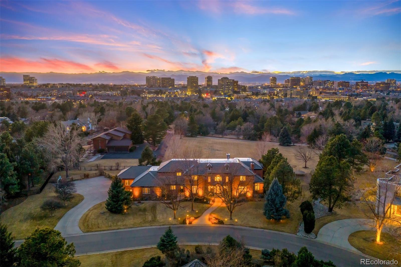 Set on one of the most coveted lots on the east side of I-25, this nearly 11,000 square foot, 6-bedroom, 9-bathroom Greenwood Village generational estate boasts stunning mountain and city views creating an extraordinary backdrop for elevated living and exceptional entertaining. Backing directly to Hoffman Park, the property enjoys the rare luxury of protected parkland, offering privacy and openness without the maintenance of additional acreage. A dramatic entry with dual staircases introduces the home’s scale and architectural presence. The main level has been thoughtfully opened to create seamless flow between the great room, entertaining areas and recently remodeled gourmet kitchen. The floor-to-ceiling windows frame the mountain views, providing a natural backdrop for both intimate and large-scale gatherings. Two main-floor offices with fireplaces provide refined work-from-home flexibility, complemented by a private guest suite. Upstairs, the 1,500SF primary retreat features balcony access, panoramic views, a sitting area with fireplace, a grand walk-in closet with space to create your own private dressing retreat, a panic/safe room, and a recently remodeled bath with heated floors and steam shower. Three additional bedrooms complete the second level, each with a walk-in closet and en-suite bath. The lower level is purpose-built for hosting, featuring a 500-bottle wine cellar, entertaining bar/kitchenette, expansive media and game area with fireplace, gym, powder bath, guest suite with private bath, abundant storage, and an indoor golf driving range. Outdoors, an extensive patio with hot tub overlooks the park and mountains, an exceptional setting for sunset evenings and year-round entertaining. A 6-car garage and extended driveway provide ample space for guests and collectors. Ideally located with convenient access to the Denver Tech Center, Cherry Creek State Park and top-ranked Cherry Creek Schools: Cherry Creek High, Campus Middle, and Belleview Elementary.