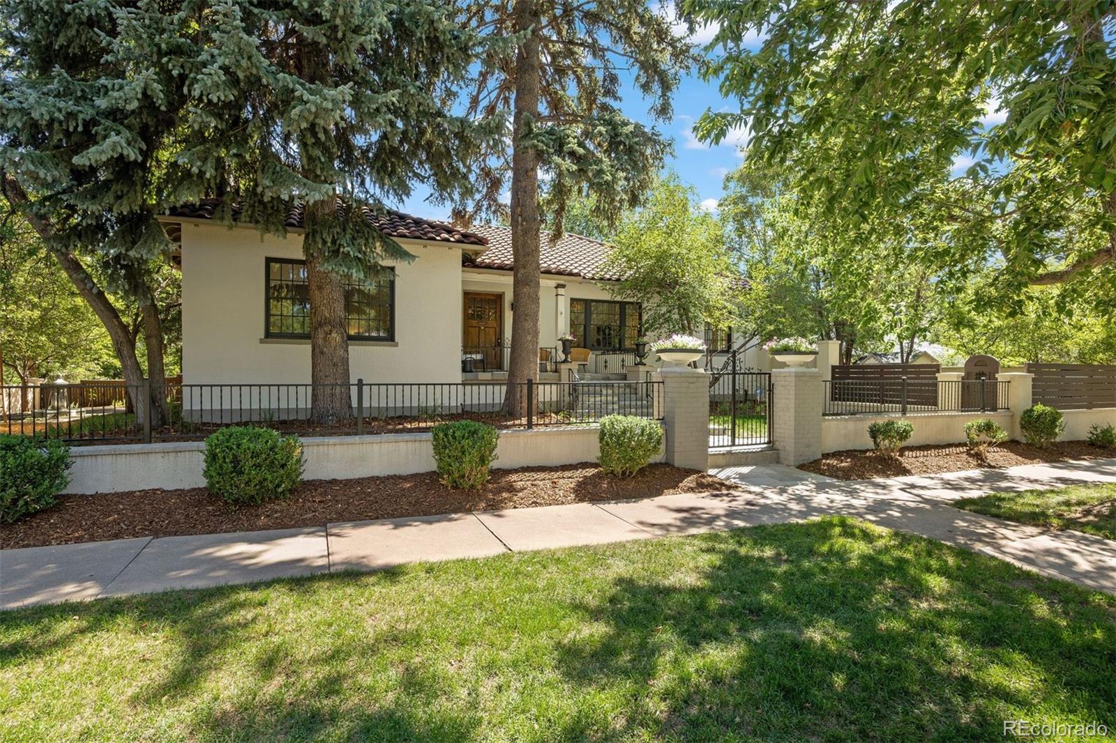 Mediterranean masterpiece spanning prestigious 7th Avenue Parkway. This exceptional residence showcases classic Spanish architecture. Distinctive design elements include -Terracotta Spanish roof, White stucco exterior and interior features, rustic wood gates, iron fencing, water features, architectural archways, and mosaic tilework and coffered ceilings.Nestled behind a gated entrance and stucco privacy wall, the home welcomes you with a beautifully landscaped private oasis, two water features, outdoor lounge, children’s playhouse, grassy areas for entertaining or play—an ideal setting.A rustic front entry door sets the tone for the home’s warmth and character. Inside, the main level offers a versatile floor plan. Formal living and dining rooms provide refined gathering spaces, with the dining room showcasing original built-in storage that adds both charm and functionality. The inviting family room is centered around a stucco-surround gas fireplace adorned with mosaic accents.The updated kitchen is elegantly appointed with marble countertops, a Liebherr refrigerator/freezer, a Bertazzoni range, a cozy eat-in nook, and a spacious pantry—perfectly suited for a beverage bar or additional storage.Three generously sized bedrooms are located on the main level, including a well-appointed primary suite. The expansive finished lower level offers exceptional flexibility, featuring a large family or entertainment room with a second mosaic-accented fireplace, two additional bedrooms or office spaces, a full bathroom, and a versatile bonus room ideal for a fitness area, playroom, or art studio. A dedicated laundry room and mudroom enhance everyday convenience.Additional highlights include a whole-house water filtration system, finished two-car garage and an unparalleled location just moments from Cherry Creek, the Denver Botanic Gardens, and numerous parks. The property is also situated within the highly sought-after Bromwell Elementary and East High School districts.