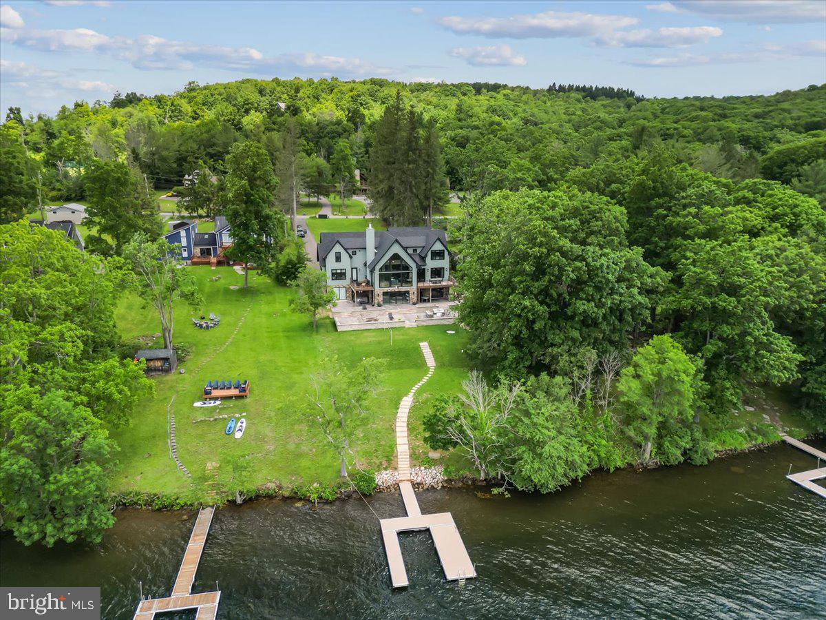 Welcome to "Stone Manor", one of Deep Creek Lake's most extraordinary waterfront estates.Custom built in 2023 by renowned builder Don Nemith and beautifully curated by Juniper Interiors, this remarkable lakefront retreat blends timeless craftsmanship, luxury design, and exceptional investment potential. Situated on nearly an acre with 108.9 feet of level lake frontage and a coveted Class A private dock, the property offers over 8,300 square feet of thoughtfully designed living space in one of Deep Creek Lake's most desirable locations.Paying homage to the property's rich history, the owners incorporated stone from the original Stone Manor into the construction and landscape design, creating a one-of-a-kind residence that honors the past while delivering every modern luxury imaginable.Inside, you'll find 5 bedrooms, 6 full baths, 1 half bath, soaring ceilings, expansive gathering spaces, designer finishes, and walls of glass that frame breathtaking lake views throughout the home. The spectacular indoor pool creates a true four-season resort experience, while multiple indoor and outdoor entertaining areas were designed for unforgettable gatherings with family and friends.The exterior is equally impressive, featuring extensive custom hardscaping, an outdoor kitchen, multiple lakeside entertaining spaces, and easy access to the private dock just steps from the home. A massive 4-car garage provides exceptional space for vehicles, boats, lake toys, and storage.Currently operating as the highly successful Stone Manor vacation rental, the property has generated an average of $201,000 in annual gross rental revenue, offering established income potential alongside luxury lakefront ownership.One of the few newer luxury homes on Deep Creek Lake offering a Class A dock, indoor pool, and proven six-figure rental history, Stone Manor presents a rare opportunity to own a private waterfront resort in the heart of Deep Creek Lake. Conveniently located just minutes from Wisp Resort, golf, marinas, restaurants, and year-round recreation.Offered fully furnished and turnkey. Shown by appointment only. Call today for your private tour.