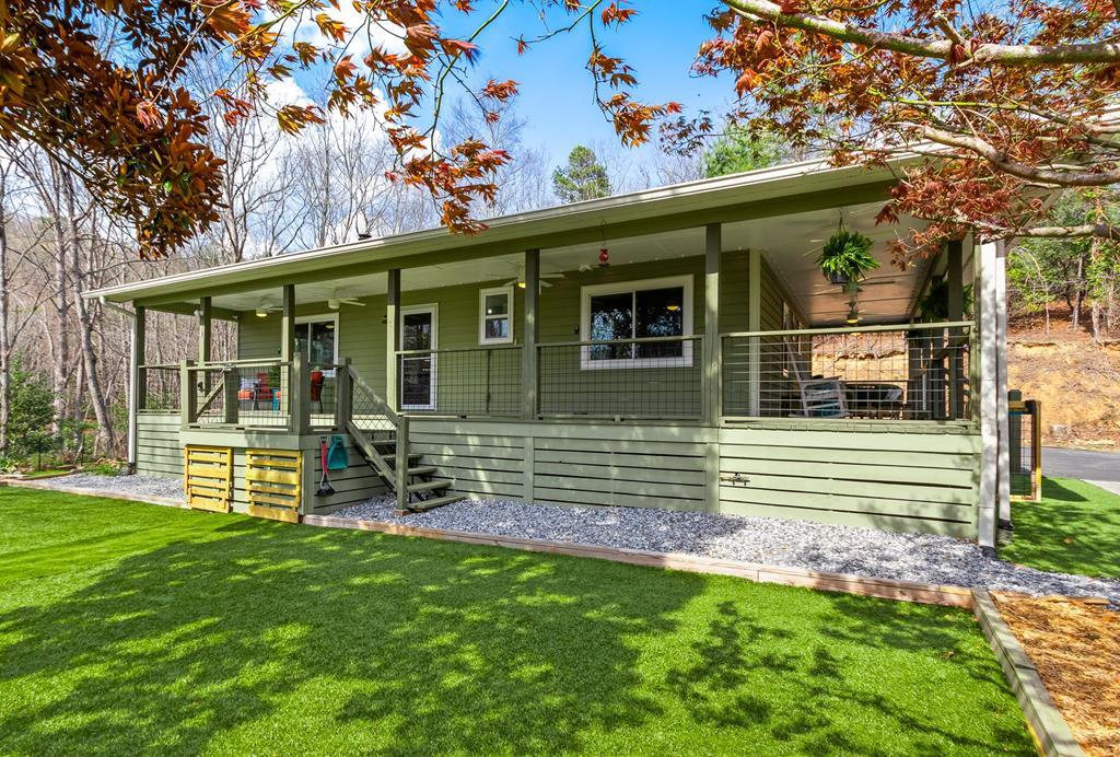 On two lots totaling almost 5 acres, this versatile property with TWO HOMES offers space, functionality, and a LONG-RANGE MOUNTAIN VIEW. The main residence features 2 bedrooms and 2 bathrooms, plus two flexible bonus rooms. A full-length front porch wraps around two sides of the home, creating a welcoming entry and ideal spot to take in the scenery. Inside, the bright, open Great Room showcases vaulted tongue-and-groove ceilings, luxury vinyl flooring throughout, a surround-sound system, and a dramatic floor-to-ceiling wood-burning fireplace. The adjoining kitchen is designed for both everyday living and entertaining, with abundant cabinet and counter space, a center island with seating and storage, stainless steel appliances, an apron sink, and direct access to the screened back porch with a ramp. The layout offers privacy and convenience, with a guest bedroom and bath on one side, along with a laundry area, and the spacious Master Suite that  includes its own en suite bathroom. Across the Great Room are TWO bonus rooms that extend the living space—one with direct access to the side deck and hot tub, and another currently used for storage with a doggie door for Fido. Outside, you'll find a paved driveway with lots of parking space, a single carport, and a detached garage with workshop space, power, and additional storage. The secondary home is FULLY FURNISHED and has 2 bedrooms, 1 bathroom, a Great Room, and an open kitchen with stainless steel appliances. Recent upgrades include new windows in 2025 with a transferable warranty, NEW ROOFS on both homes in 2021, and an on-demand water heater for efficiency in the smaller house. Fiber Optic internet is expected in the area soon, adding even more appeal to this exceptional property.