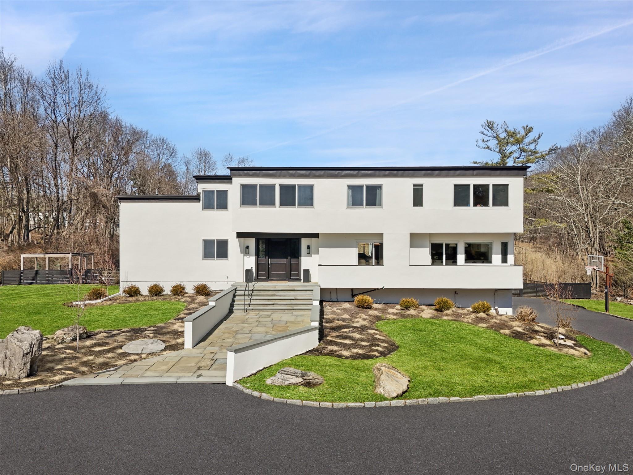 A serene, light-filled retreat where modern design meets timeless comfort, this exceptional  four bedroom four and one half bath contemporary residence offers an elevated lifestyle in one of Chappaqua’s most coveted settings.Set along a premier Chappaqua road on nearly three acres, the home is defined by its airy interiors, soaring ceilings, light hardwood floors throughout, and walls of windows that invite the outdoors in, framing tranquil, park-like views from nearly every vantage point.At the heart of the home, a beautifully renovated, oversized white Chef's kitchen with center island and sunlit breakfast area opens seamlessly to a dramatic family room with fireplace and multiple exposures. The main living spaces are gracious and interconnected, each oriented toward the lush, verdant grounds, offering a true indoor-outdoor lifestyle. A separate lower-level recreation or media room with direct access outside provides additional flexibility and ease. Sliding glass doors throughout lead to the yard creating an effortless flow for everyday living and elegant entertaining.The second level reveals a sophisticated primary suite with vaulted ceilings, custom built-ins, dual walk-in closets, and a spa-inspired bath. Additional bedrooms are generously scaled, complemented by a dedicated home office and versatile bonus spaces suited to today’s needs.A sweeping driveway and beautifully landscaped property enhance the home’s sense of privacy, while its location offers exceptional convenience—just moments to town, train, and top-rated schools.A rare offering that captures the essence of refined suburban living with all that Chappaqua has to offer.