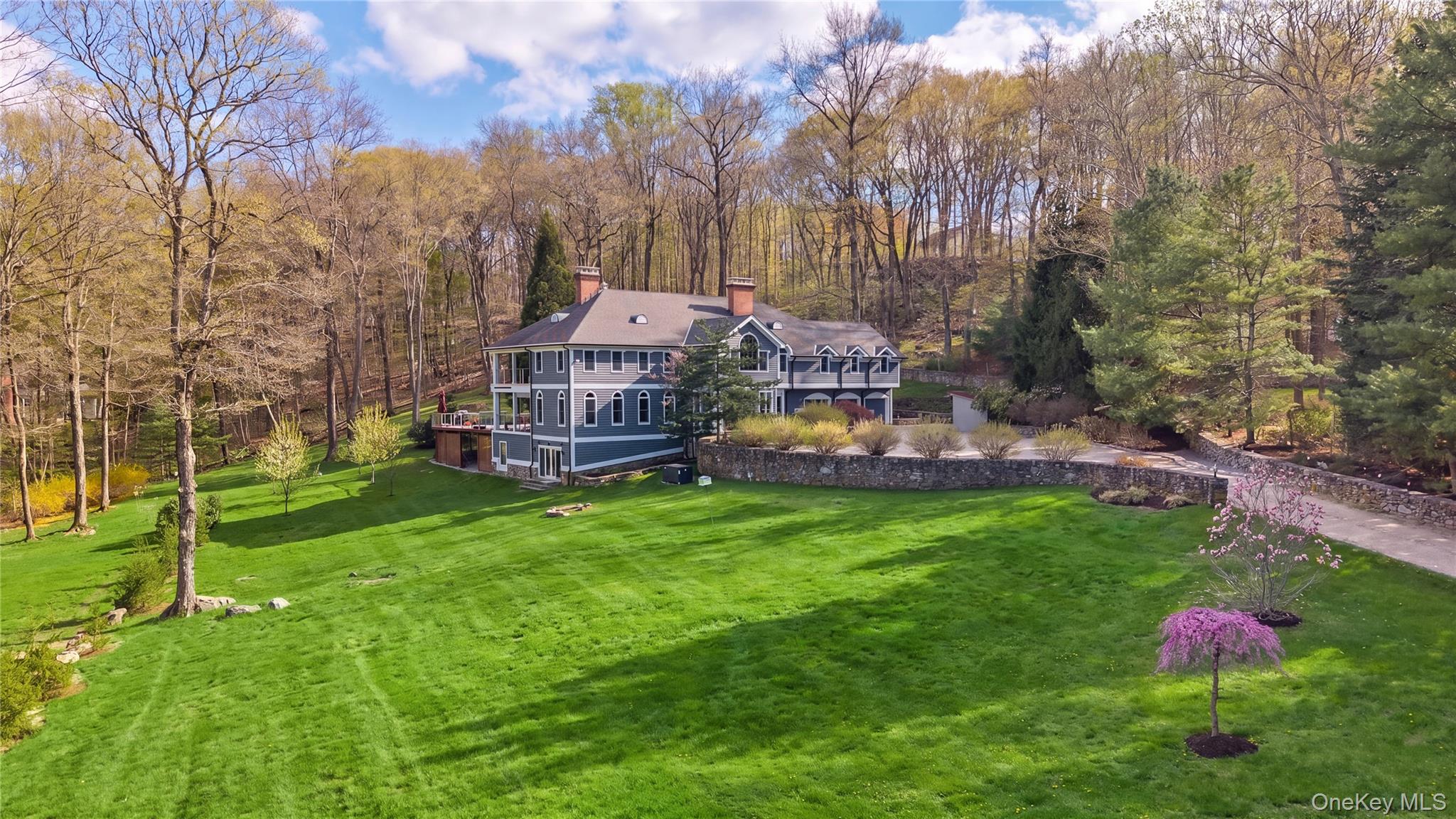 Looking for a private and expansive luxury home in Pound Ridge with a pool and open protected land? Set at the end of a long, gravel drive, this sun-filled residence offers exceptional privacy and an easy indoor-outdoor lifestyle on big land. High ceilings, hardwood floors, and French doors from the principal rooms open seamlessly to an expansive entertaining deck.The thoughtfully renovated and expanded kitchen is elegantly appointed with custom cabinetry, stone countertops, an oversized island, a Wolf 8-burner range with double ovens, and a full Sub-Zero refrigerator and freezer. A reverse osmosis water system and integrated Sonos sound complete the space.The adjacent gracious gathering room anchored by a wood stove opens directly to the deck, creating a natural flow for both intimate living and larger scale entertaining. Outdoors, a solar-heated pool and expanded wrap around deck with a pizza oven from Tarry Lodge offer a relaxed open setting in the quiet of nature.The primary suite is a peaceful retreat, featuring a covered porch and a marble spa bath with radiant heated floors. A wide hallway, front and rear stairs leading to multiple guest bedrooms and full laundry room make up the second floor. The fully finished lower level (approx. 2,400 sq ft) dressed with wood finish wainscoting is designed for flexibility, with a full bar and kitchenette, multiple flex spaces, a private guest or office room with radiant heat. The full bath with laundry hookup and separate entrance complete the large space. Bordering protected conservation land, the property offers tranquility while remaining just minutes to Scotts Corners, Bedford Village and Stamford. A wonderful Pound Ridge home where privacy, scale, and effortless living come together seamlessly.