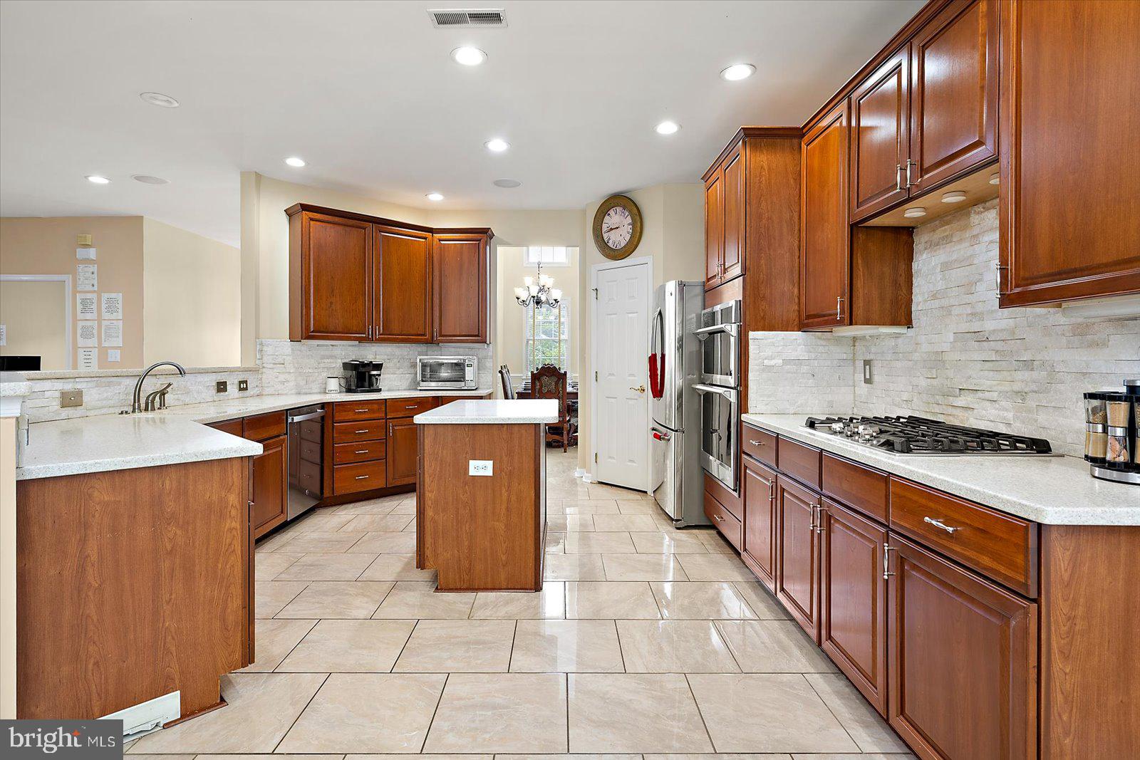 Major Price Reduction -  Located in the sought-after community of The Landings at Bayside, 8705 Habitat Court in Berlin, MD is a beautifully maintained 5-bedroom, 3.5-bath coastal home nestled on a quiet cul-de-sac. The spacious main level welcomes you with updated ceramic tile flooring and a thoughtfully designed layout ideal for both entertaining and everyday living. The gourmet kitchen features stainless steel appliances, a gas cooktop, double oven, and a custom tile backsplash above the stove, creating a distinctive focal point. The kitchen flows effortlessly into the eat-in breakfast area, formal dining room, and a cozy living room with a fireplace.The main-level primary suite is a serene retreat complete with a vaulted tray ceiling, a walk-in closet with custom cabinetry, and a spa-inspired bath featuring a soaking tub, separate shower, and double vanity, offering the perfect combination of luxury and functionality. Also on the main level are a guest half bath and a dedicated office, which opens to a large deck, ideal for enjoying sunsets. The lower level expands the home’s functionality with a second primary suite, three additional bedrooms, two full bathrooms, a second living area, and a generously sized laundry room. You'll find ample storage throughout the home, including an oversized garage with a storage area, ideal for all your coastal gear and hobbies. Outside, a generous side yard with untapped potential for space to relax, garden, or entertain. This home has low HOA fees and taxes, making it a perfect primary residence, second home, or investment property—especially with short-term rentals permitted. The Landings at Bayside is a resort-style community offering exceptional amenities, including a clubhouse with heated indoor and outdoor pools, a fitness center, game room, tennis and basketball courts, nature trails, a crabbing pier, a stocked fishing pond, and a kayak launch. Enjoy panoramic bay views from two community docks and convenient access to Ocean City beaches, Assateague Island, and historic downtown Berlin. With lawn care and trash service included, this home provides a low-maintenance lifestyle in a vibrant coastal setting. The home is being sold unfurnished, but the seller is open to selling furniture separately.