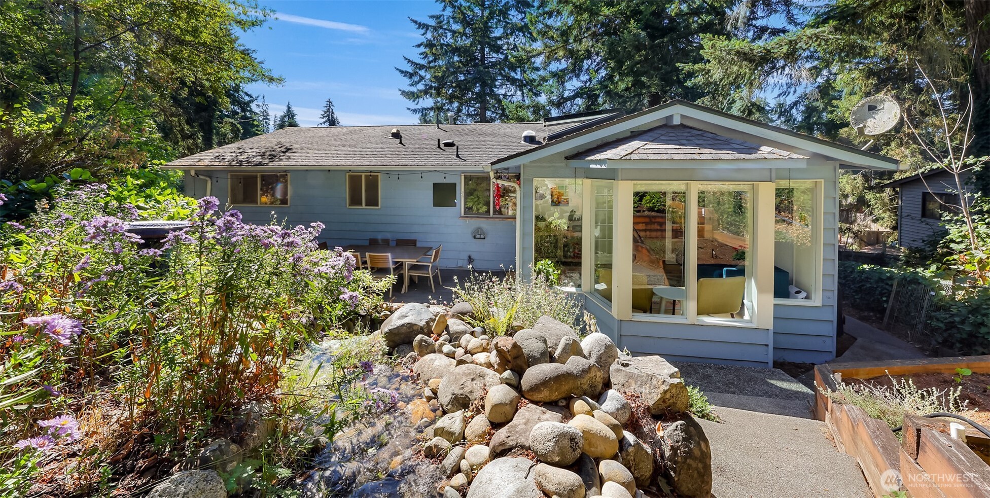 Welcome to The Waterfall House: Updated throughout and set in one of Edmonds’ sought-after school zones, this home is just minutes from the popular Klahaya Swim & Tennis Club. The open kitchen anchors the main living spaces and is complemented by updated bathrooms with custom tile work, engineered vinyl plank flooring, newer windows and appliances, and a new electrical panel. In the kitchen, ample quartz counters, quality cabinetry, open shelving, and a butcher block island create a warm and functional gathering space. A pass-through window connects the kitchen to the patio, making entertaining easy. Main-level living includes three bedrooms and a full bath, plus a primary suite with its own updated bath and custom tile. A large living and dining area are anchored by a gas fireplace. A sunny sunroom overlooks the backyard and deck, where a terraced garden w/ a running waterfall leads to a private patio perched above the house—perfect for morning coffee. The lower level adds functional flexibility w/ a music room, office nook, spacious rec room warmed by a woodstove, half bath, & stacked laundry. Outside, apple and cherry trees, raised vegetable beds, drip irrigation, & a new fence create a garden that is as productive as it is beautiful. The generously sized two-car garage is joined by four off-street parking spaces. Skylights and solar tubes bring natural light throughout, while the location puts you close to I-5, Costco, downtown Edmonds, & neighborhood parks.