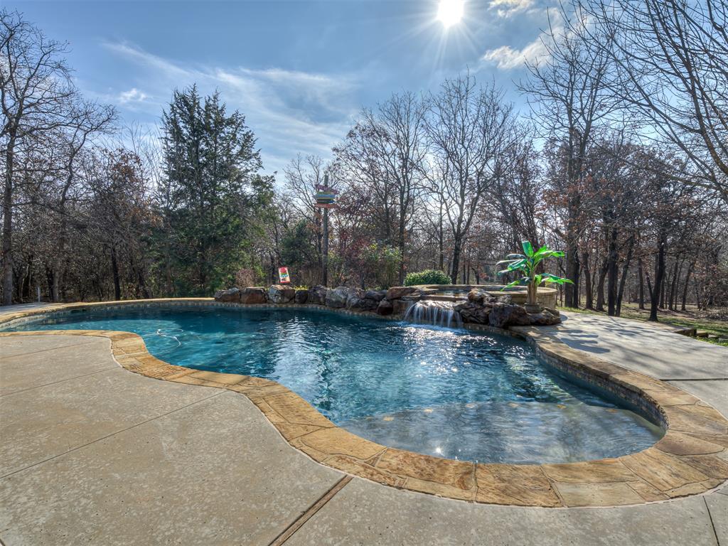 Welcome to your personal oasis!   This place has it ALL!  Sitting on over 4.3 wooded acres this home feels very private and secluded, yet it's close to I-35 and all the amenities Edmond has to offer.  There are 4 bedrooms, all of which are connected to a bathroom, there's also a separate office, a formal dining room, an upstairs bonus room with a full bathroom connected and even an additional separate space that could be used as a hobby room.  There is a beautiful view outside every window in the house.  The living room has a vaulted ceiling with wood beam accents and floor to ceiling windows showcasing the absolutely amazing backyard!  Under the enormous covered back patio is a gorgeous stone fireplace.  There is an outdoor kitchen and dining space next to the picture-perfect pool and spa which overlooks the beautiful, wooded backyard.   The oversized three car garage has insulated garage doors and a storm shelter in the floor.  This property is an absolute MUST SEE, located in the serene gated Tanglevine neighborhood.