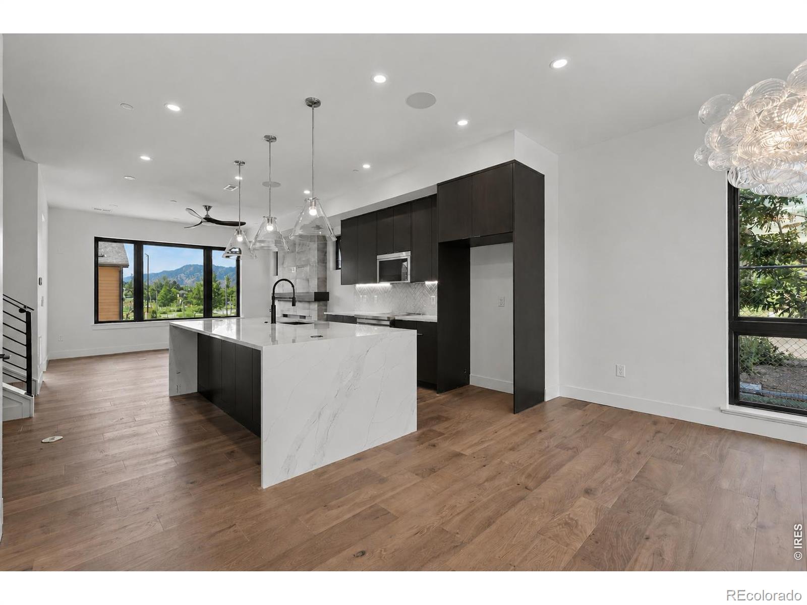 Experience elevated living in this stunning end-unit townhome, where sweeping Flatirons & foothills views take center stage. With coveted southern & western exposure, abundant sunlight fills the home through expansive windows, framing Boulder's iconic mountain landscape. Blending sophisticated design, exceptional craftsmanship, & sustainable living, this exceptional residence offers an unparalleled lifestyle in the heart of North Boulder. Enjoy easy access to Pearl Street, Wonderland Lake, Lucky's Market, Foothill's park, & miles of scenic hiking & biking trails moments from your front door. Step inside to an open-concept main level designed for effortless living & entertaining. The modern kitchen features waterfall-edge quartz countertops, custom cabinetry, premium appliances, designer lighting, & wide-plank wood flooring, flowing seamlessly into the dining & living areas. The light-filled living room is anchored by a sleek electric fireplace with a custom tile surround, creating a warm & inviting focal point. On the 2nd level, wake up to foothills views from the north-facing primary suite, while the south-facing suite enjoys beautiful Flatirons vistas. The 3rd level serves as a penthouse retreat featuring a spacious bedroom & ensuite bath. Perfect as a guest suite, home office, or bonus living space, this level opens directly to the expansive treetop deck - an unforgettable setting for morning coffee, evening sunsets, & entertaining against NoBo's breathtaking backdrop. Outdoor living is equally inviting with a welcoming front patio & a generously sized, fully fenced backyard - perfect for dining, pets, or simply enjoying Colorado's sunshine. Located to the South of the future site of BMoCA, steps from NoBo Arts District, Moxie Bread, Spruce Confections, Dagabi, Cinq Sept, Proto's Pizza, Yoga Pearl, & more. Built by award-winning Koelbel Communities, this home reflects generations of Colorado craftsmanship backed by the Koelbel family's legacy since 1952. Sales Tr