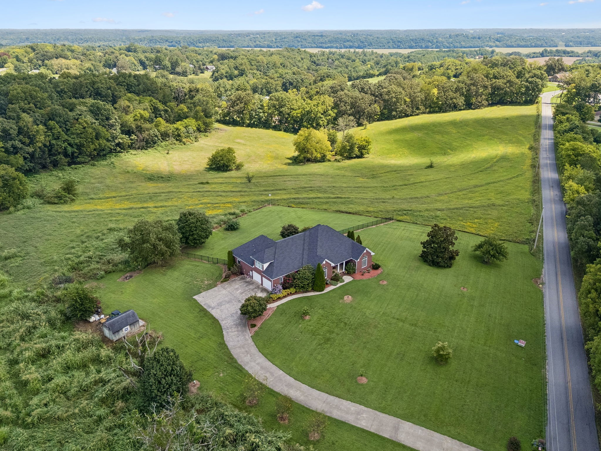Custom-built, one-owner, all-brick ranch with bonus room on rolling 19.45 acre farm with spring fed pond and over 2200 feet of country road frontage on McClure and Chapel Hill Roads. Property is mostly fenced, perfect for raising cattle, with additional, separate fenced back yard space behind home. Inside you'll find four spacious bedrooms and three and 1/2 baths. Open living, kitchen and breakfast room space, formal dining, and split bedroom plan for privacy. The 10x25 screened porch area and 8x25 concrete patio overlook rolling hills and sunrise to the east. The bonus room with door and half bath would make for great guest suite or office space. Walk-in attic space could be future expansion potential. Enjoy established landscaping to include cherry and fig trees, berries, many flowering shrubs and perennials, and garden space. All located within a short drive to grocery, parks, or to downtown Clarksville.