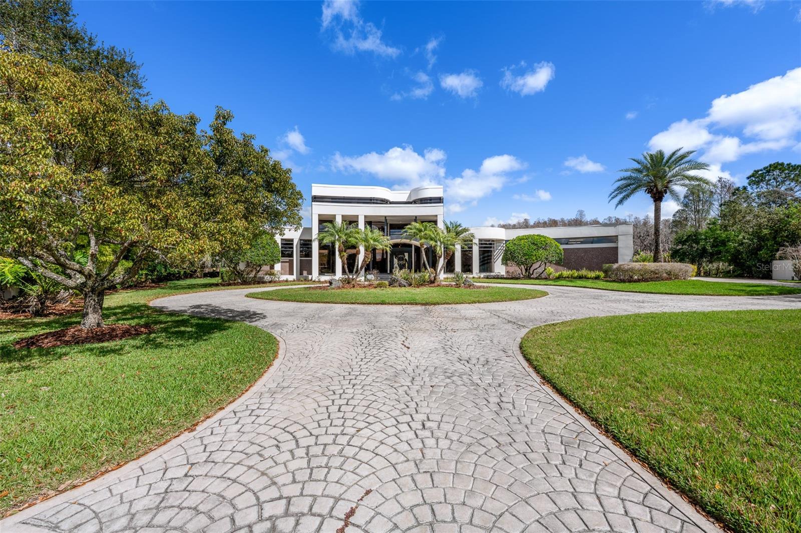 Tucked behind the gates of Cheval Polo & Golf Club, where oak-lined streets meet championship fairways, this extraordinary estate invites a life defined by space, privacy, and quiet luxury.Positioned on over an acre at the end of a cul-de-sac, the home unfolds with a sense of scale that is both impressive and intentional, offering more than 8,200 square feet of living space with sweeping pond and golf course views. Mornings begin with soft light over the water, coffee in hand as the day eases in, while afternoons transition effortlessly between indoor comfort and outdoor escape.Designed for both grand entertaining and everyday living, the residence balances grandeur with warmth. Soaring ceilings, refined architectural details, and expansive living spaces create a backdrop that feels both elevated and inviting. The kitchen anchors the home—open, functional, and designed for gathering—with stone countertops, a large center island, and seamless connection to the surrounding living areas, while formal spaces provide flexibility for hosting on any scale.The primary suite offers a true sense of retreat, privately positioned on the main level with generous proportions, dual walk-in closets, and a spa-inspired bath featuring a soaking tub, separate shower, and dual vanities. Each additional bedroom is thoughtfully designed with its own en-suite, ensuring comfort and privacy for family and guests alike.Outdoor living is equally compelling, where a screened pool and spa, outdoor kitchen, and expansive patio spaces create a private, resort-like setting designed to maximize tranquil golf and water views. Mature landscaping, a circular drive, and a four-car garage further enhance both presence and functionality.Beyond the home, Cheval offers a lifestyle few communities can match, with 24-hour guard-gated security, championship golf, tennis, and a setting that feels worlds away while remaining effortlessly connected to Tampa’s best dining, shopping, and top-rated schools.A rare opportunity to own a property of this scale and setting within one of Tampa Bay’s most sought-after communities—designed to live expansively and exceptionally well.