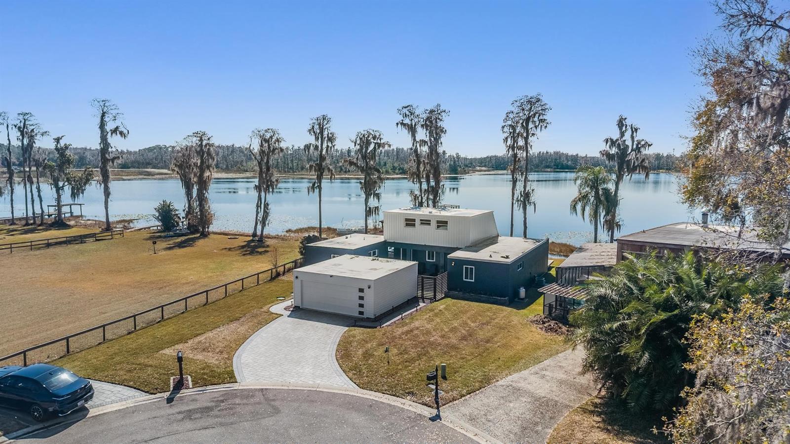 Experience true waterfront living on beautiful Lake Stemper, a private ski lake offering year-round boating and water recreation. With only approximately 20 homes lining its shoreline, this rare lakefront opportunity offers both exclusivity and privacy. Tucked away on a quiet cul-de-sac, this fully updated modern lakefront home blends clean architectural lines with effortless indoor-outdoor living. Designed around a private courtyard, the sparkling heated saltwater pool creates a secluded retreat at the heart of the home—perfect for entertaining or relaxing in total privacy. The pool and surrounding pavers were installed and sealed in April 2022 and resealed in April 2024, adding both beauty and long-term durability to the outdoor space. Step inside to an open-concept layout featuring soaring ceilings, contemporary finishes, custom indoor shades, and a ProFlame electric fireplace with remote control for effortless ambiance. The beautifully renovated kitchen showcases sleek cabinetry and stainless steel appliances. Expansive windows flood the interior with natural light, while breathtaking water views immediately capture your attention. Sliding doors guide you seamlessly outdoors to a fully equipped outdoor kitchen (2022) featuring a Blaze 4-burner propane grill, flat top and side burner, sink, ice maker, and granite countertops accented with LED lighting strips underneath. Just beyond, a spacious deck leads to your private covered dock (2022), creating the ultimate lakeside entertaining space. Whether you're hosting sunset dinners, launching your boat for a day on the ski lake, or simply enjoying the peaceful setting, this property was designed to embrace lakefront living. A standout feature is the detached ADU, complete with its own private entrance and kitchenette—ideal for guests, multigenerational living, a home office, or added flexibility. Major improvements include a new septic tank and drain field completed in 2025, offering added peace of mind. This is modern Florida lakefront living—private, updated, and perfectly positioned on one of the area’s most desirable ski lakes.