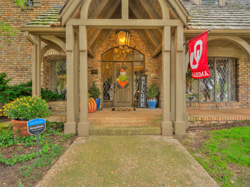 Timeless Tudor Revival in Whispering Pines just steps from OU’s campus. This 5-bedroom, 3.1-bath home offers over 4,600 sq. ft. of beautifully crafted living space on a corner lot. Grand ceilings and walls of windows fill the home with natural light, while rich wood details and a wine cellar add warmth and charm. The gourmet kitchen boasts custom cabinetry, premium stainless appliances, and a built-in pizza oven (a favorite) — perfect for entertaining. Retreat to the luxurious primary suite with a spa-inspired bath featuring a clawfoot tub, walk-in shower, and generous closet. Upstairs, a Jack-and-Jill bath connects two bedrooms, plus a hidden bunk room offers extra space for guests or play along with a second living room with a beautiful stone fireplace and a wet bar. Enjoy outdoor living around the private pool surrounded by mature trees. A true blend of old-world character and modern comfort in the heart of Norman.