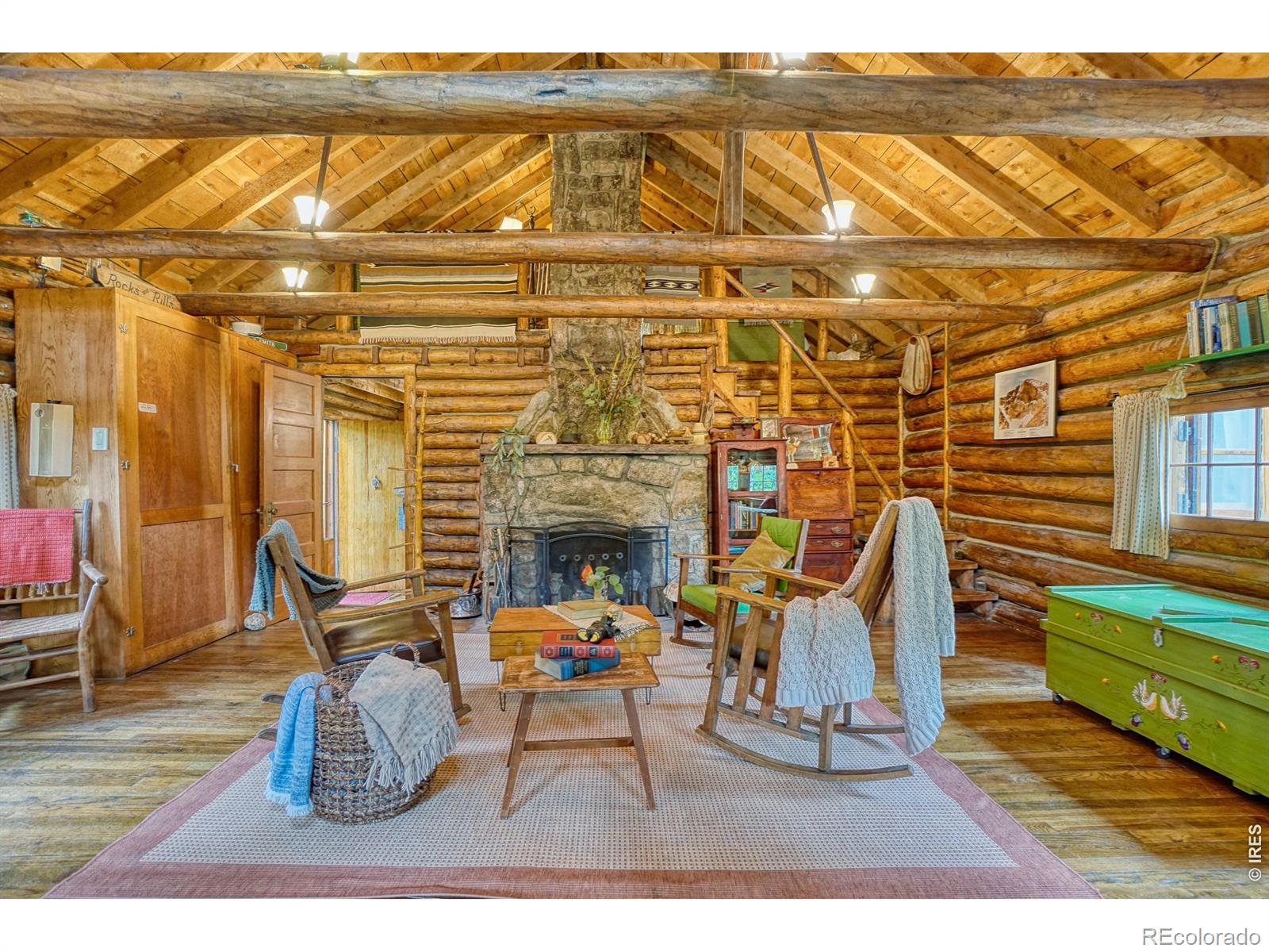Imagine curling up in front of a roaring stone fireplace beneath dramatic, hand-hewn wood beams or getting lost in a good book in the charming loft, surrounded by the warmth and character of a true Colorado log cabin. In the picturesque town of Raymond, this cozy 1-bedroom, 1-bath retreat is nestled in the woods, with a seasonal stream running through the property and the river just a stone's throw away.Large windows above the kitchen sink open completely to the outdoors, inviting fresh mountain air as you cook, gather, and enjoy the feeling of being outside while still tucked into the comfort of home. Listen to the stream, share stories by the fire, and savor peaceful moments surrounded by nature.An addition completed in 1968 added modern comforts, including a bathroom and extra sleeping space, while preserving the cabin's authentic charm. Thoughtful updates include a septic system installed in 2012, a newer boiler for baseboard heat, and a newer hot water heater. This is a place for gathering with family and friends, creating traditions, and enjoying the simple romance of life in the woods-with all the modern amenities.