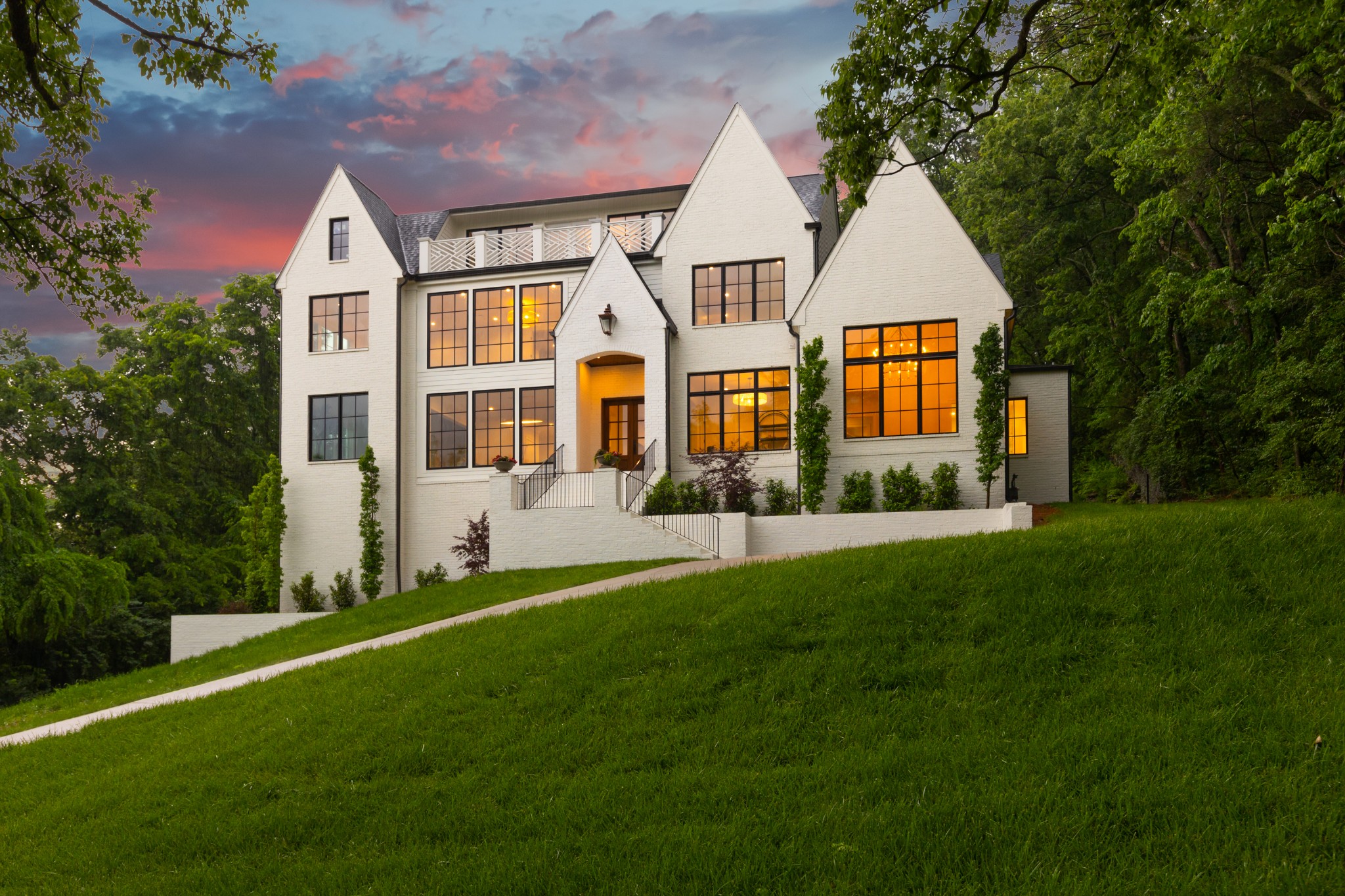 Elevated in every sense, 4527 Wayland Drive offers a rare opportunity to experience refined seclusion in one of Nashville’s most coveted hidden enclaves. Tucked into the lush, rolling terrain of Harpeth Hills, this estate-caliber property blends quiet luxury with timeless materials and curated design.From the moment you enter, you're greeted by panoramic green views from every room, creating a backdrop that feels like a private resort in the city. Inside, Calcutta honed marble, white oak flooring, vaulted ceilings, and designer lighting set the tone. The chef’s kitchen is a study in elegance and function, featuring Wolf appliances and seamless flow to open-concept living spaces.The primary suite is a vaulted retreat with spa-like finishes and natural light that pours in from every angle. The open layout flows effortlessly to a rooftop balcony, creating the ideal setting for entertaining. A three-car garage, smart layout, and exceptional craftsmanship round out this rare offering.