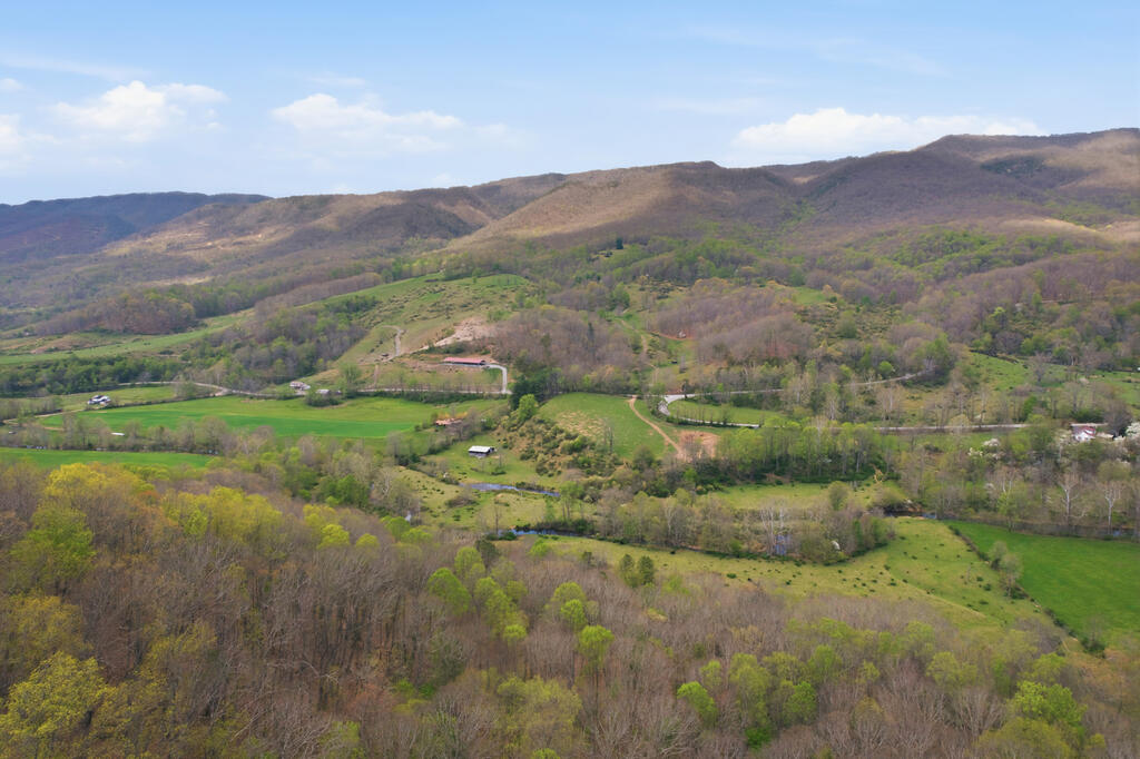 A beautiful historic family farm in the heart of Tannersville within Tazewell County, this sprawling 493 +/- acre property delivers agricultural possibilities, comfortable living, and true mountain recreation. The parcel reaches across both sides of Freestone Valley Road, giving the new owner plentiful road frontage, and several established gated access points. The property also carries relatively level, highly visible frontage along Route 16, a popular road for mountain driving.  The owners currently lease ground for cattle grazing and row crops.  The farm offers wide-open pasture and established fencing (although fencing needs some TLC in areas)  The mountains have marketable timber and varied terrain, providing plenty of recreation and wildlife, even adjoining the National Forest on the Southern boundary.  The family farm includes a spacious five-bedroom, two-bathroom main home built around an open, light-filled living area with abundant windows framing long-range valley and mountain views. A screened porch and attached garage add everyday comfort and convenience. A separate bunkhouse offers flexible space for extra guests or hunting parties and an additional bathroom.  This extra space holds real potential as an overnight rental for visitors drawn to the region's outdoor attractions. The home uses a private well and septic system, with access to a year round spring in addition to the well. A large barn provides ample room for equipment and ongoing agricultural use. Water resources here are exceptional. The farm boasts approximately 1,800 feet of frontage on Laurel Creek — including your own private island — along with multiple mountain springs and a small pond.  There is no shortage of long range views, which are absolutely beautiful!  Access throughout the property is made a little easier due to the established road beds that ATVs, Tractors and Vehicles should be able to reliably travel. Buyer/Buyers Agent should independently verify all information.