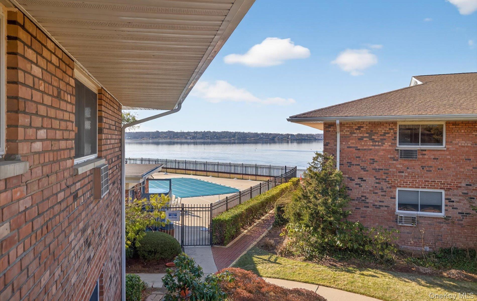 A rare opportunity awaits at Toms Point in this sun-drenched 2-bedroom corner unit, where a fresh and airy atmosphere greets you the moment you step inside. The entire residence has been professionally painted and features gorgeous hardwood floors throughout, newly refinished in a sophisticated special walnut stain. The home feels crisp and sparkling clean, offering a spacious floor plan that leads to a private balcony with a beautiful, direct view of Manhasset Bay. This sought-after waterfront perspective continues in the primary bedroom, which overlooks the bay, while the second bedroom offers a charming side view of the water. The kitchen is tidy and functional, providing a clean canvas for your choice of new appliances. While the home is move-in ready and inviting, the bathroom is in its original condition, offering a premier opportunity for the new owner to add value and personalize the space to their own taste. Residents enjoy exceptional waterfront amenities including an in-ground pool, private beach access, kayak storage, mooring rights, and a front gate attendant for added peace of mind. The grounds feature a scenic bayfront promenade perfect for relaxing walks and unforgettable sunsets. Commuting is effortless with a 36-minute LIRR express train into Manhattan, all within a vibrant town known for exceptional shopping and dining. Note the new insulated roof installed in 2024. This home is a must-see for those seeking a pristine start with a spectacular view.