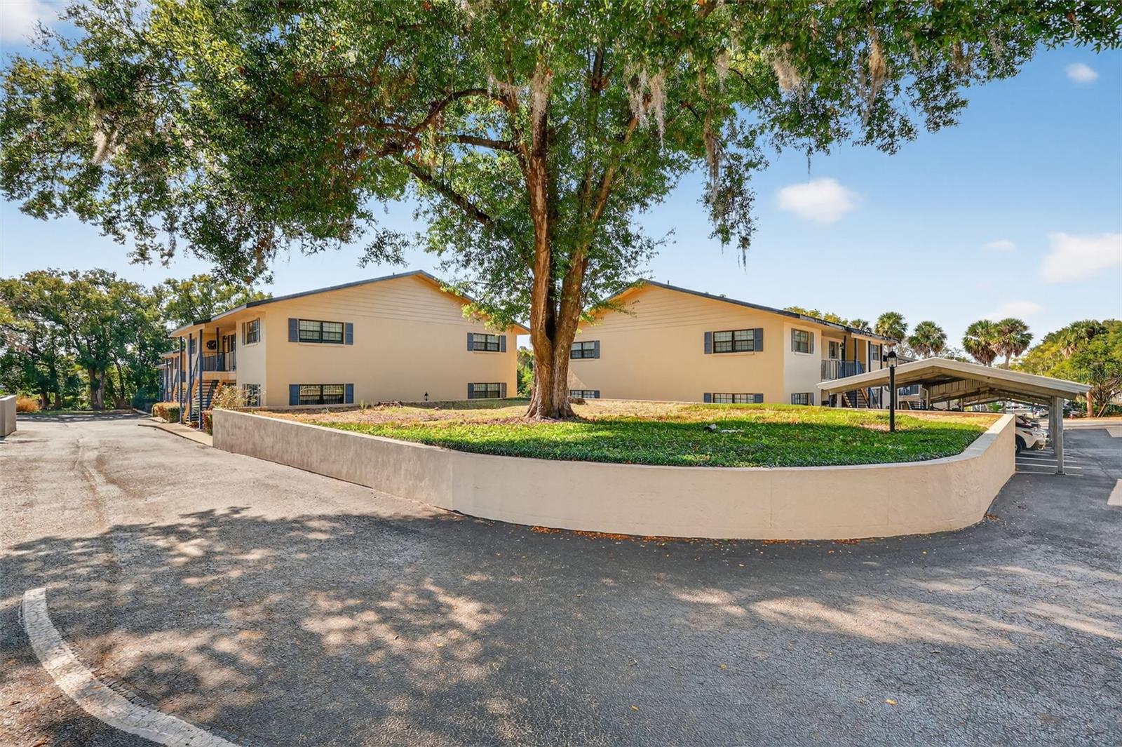 ADORABLE, AFFORDABLE, CAREFREE LIVING IN THIS CHARMING MOUNT DORA CONDO. Looking for home ownership that won’t break the bank, or perhaps a second home to chill poolside in the winter instead of shoveling snow? The Lakewood Condo community is a lovely place to call home. It is not age-restricted; its common areas are well-maintained, showing genuine pride of ownership, and the 28 units, pool, and clubhouse are nestled on a lush green lawn with palm trees and pink Bougainvillea, and are located in the renowned historic district. Often referred to as The New England of the South, Mount Dora is known for its charming, walkable downtown with historic buildings, art galleries, eclectic boutiques, and cozy cafes, but with warmer Florida weather to enjoy fun festivals, boating on Lake Dora and the Chain of Lakes, pickleball, and other great outdoor activities year-round! Park in your conveniently covered carport space, and then just a few steps will take you to your downstairs home with a covered front entry. Step through the front door into a welcoming, open interior with pleasing, neutral tones and wood-look laminate flooring throughout the living areas. Enjoy a spacious combination dining and living area with an additional sitting room with large windows for abundant natural light. There’s plenty of space for hosting family and friend gatherings, and the kitchen is well-appointed with wood cabinetry, stainless steel appliances, a breakfast bar, and a closet pantry. Enjoy ample storage space in the many interior closets, including a spacious laundry closet. The primary bedroom has two large double-door closets, multiple windows, and a private bathroom with an updated, walk-in tiled shower. The guest bedroom offers an expansive closet, large windows, and easy access to the hallway bathroom with a tub/shower. Step outside to meet up with friends at the clubhouse or by the sparkling pool. Enjoy local art, theater, boating, shopping, dining, and so much more, and then, enjoy coming home to your personal, peaceful sanctuary. Welcome home!