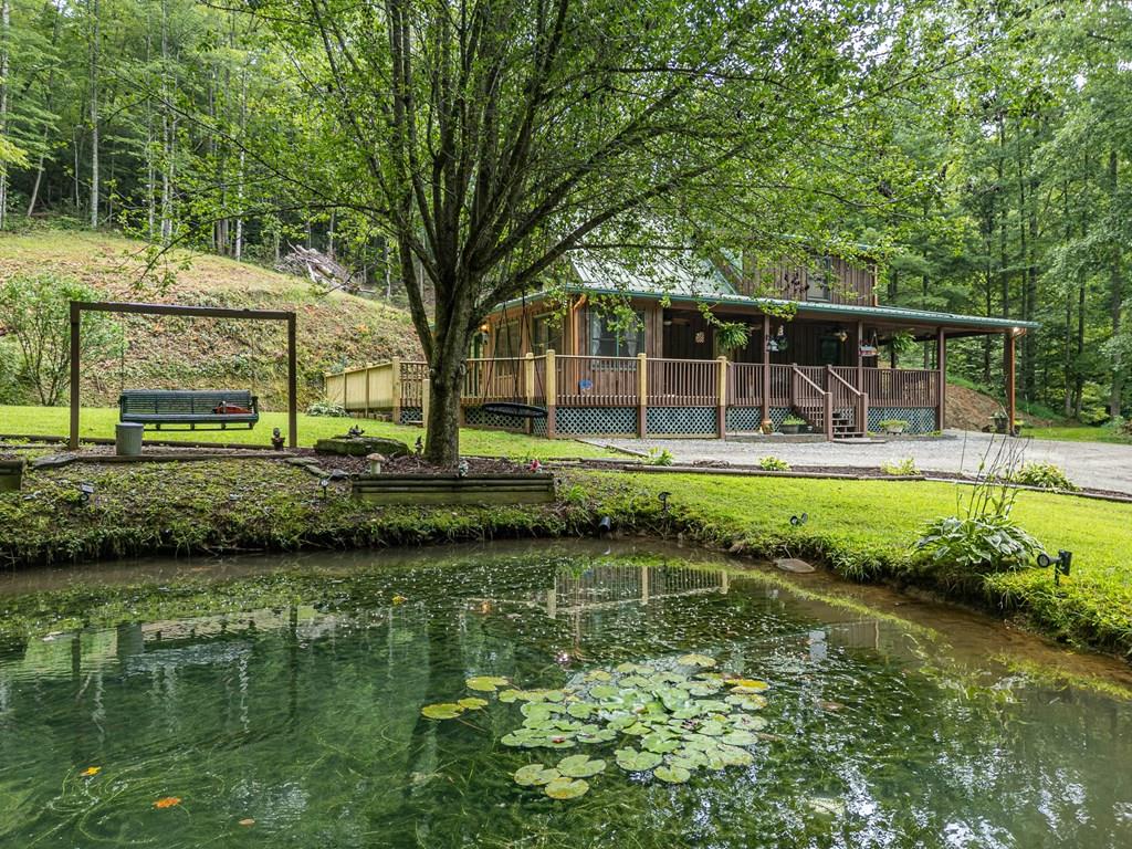 Rare 30+ Acre Mountain Retreat Bordering USFS & Cherokee Tribal Land. The property features two tranquil ponds, a small creek, open pasture ideal for gardening, and wooded areas with established four-wheeler and hiking trails throughout. Multiple potential building sites make it perfect for expanding, creating a family compound.   The charming chalet style home with a vaulted ceiling great room, 2 bedrooms with 2 baths on the main level and a large loft with a 3rd bath ready for completion.   Enjoy the outdoors from the large covered front porch—perfect for rocking chairs—or the expansive open deck out back overlooking one of the ponds. There's also an attached carport plus an additional detached carport for extra parking or equipment storage.   The oversized one-car garage with half bath could be used as a workshop or easily converted into a guest house.   You'll also find a chic chicken coop and a goat barn with fencing ready for your mini-farm dreams.   This unique property is a true retreat for those looking for a homestead, a peaceful getaway, or an adventure property, this one truly has it all—offering the perfect backdrop for a tranquil, peaceful lifestyle.