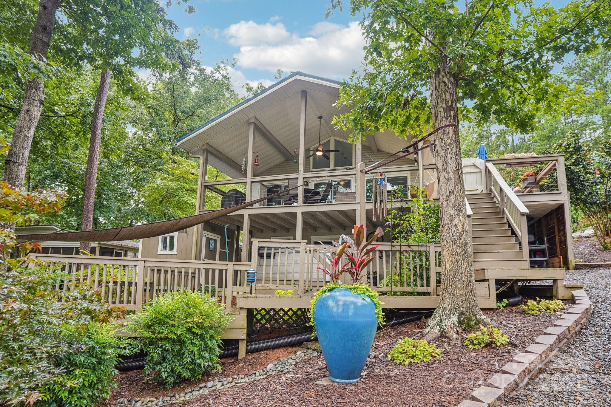 Nestled among the trees, this charming 3 bdrm, 1 bath lake house offers the perfect blend of comfort, character & outdoor living. Inside, you’ll find an updated kitchen & bath, renovated for modern living while still preserving the cozy, getaway feel of a lake retreat. The great room features abundant glass & cathedral ceiling. Outside you'll find multiple outdoor entertaining spaces: a welcoming front porch, side deck, spacious covered porch facing the water, that feels reminiscent of a treehouse, a lower-level covered patio & private deck w/ hot tub—perfect for relaxing under the stars. Follow the walkway to the water’s edge—choose between the golf cart path or steps—& enjoy a scenic stroll past a charming fire pit area & lovely landscaping. Well-appointed boathouse w/ a large storage room & one-slip, ready for all your lake adventures. Whether you're seeking a weekend escape or full-time lakeside lifestyle, this home offers the perfect balance of rustic charm & modern updates.