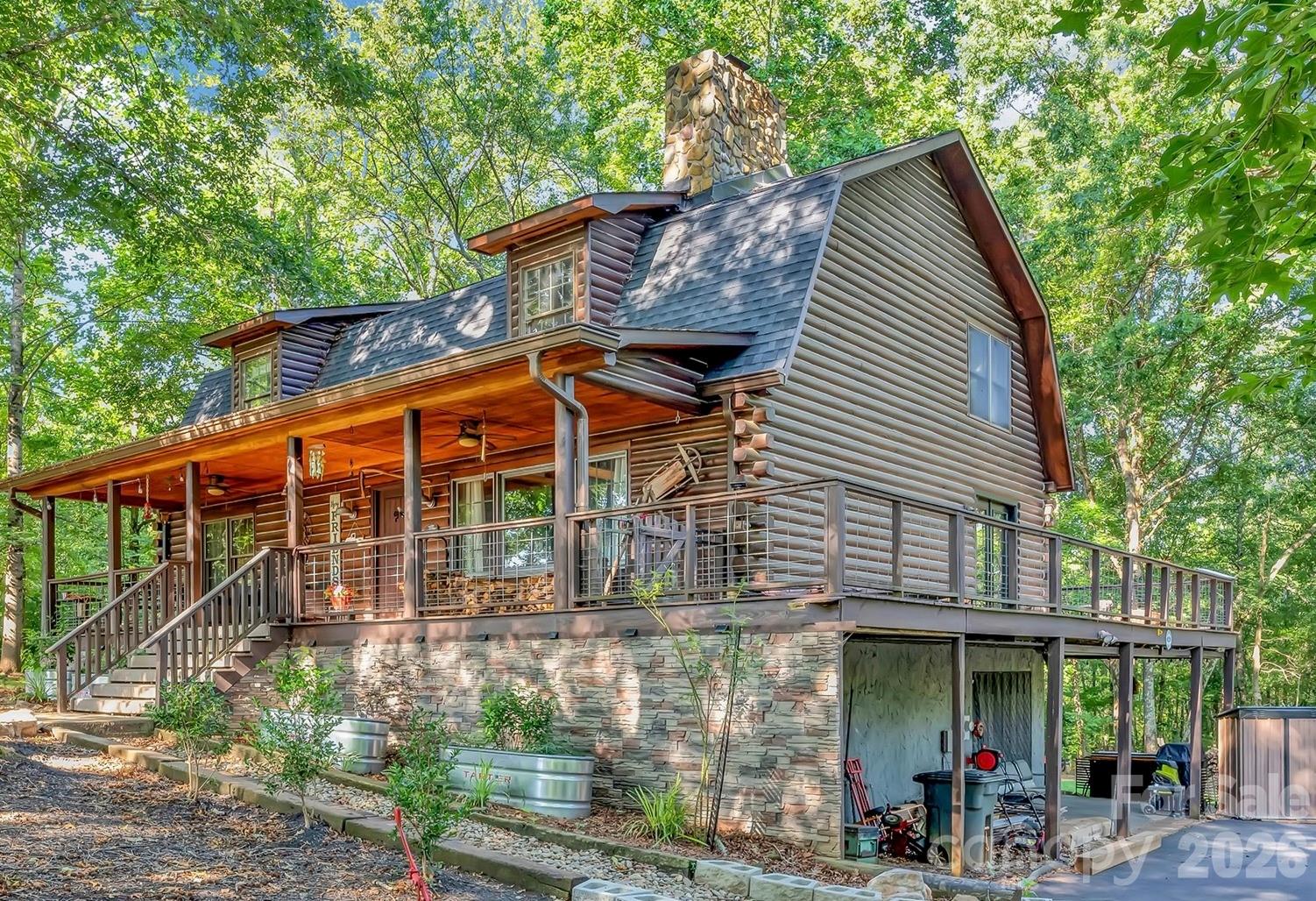 Beautiful, secluded setting features a traditional Log home on 14.6 acres, surrounded by woods, horse pastures and private fishing pond. A long driveway (1000 feet) with mountain views leads to the house in its quiet wooded setting. The house is two stories plus a full basement, features a wrap-around porch covered along the entire front, and a new roof. As you enter the house, you will enjoy the beauty of wood all around, including exposed timber beams, walls and floors. The primary suite joins the den, kitchen and dining area on the main floor, while there are two bedrooms and a huge loft upstairs, great for playroom or for entertainment. The kitchen is updated and fully set up with newer countertops and appliances. The finished basement includes a great room area, workshop, office, half bath and covered patio.  The basement bathroom is plumbed for a full bath should you want to convert it to an in-law suite. Outside, there is ample parking, including a two-car carport. A large outbuilding is set in the back yard next to areas where chickens and pigs have been raised. From the porch there are views of the pastures and the pond. The four acres with the house are zoned residential, while the remaining acreage is agricultural. Some edges of the property are fenced, while four fencible acres of pasture have held 3 horses before and are adjacent to the pond.  Lots of paths to hike, teeming with deer and other wildlife. A 10-pound bass is waiting for you in the 5-acre shared pond that borders the rear of the property. Hunt, fish, ride horses or just sit and enjoy the tranquil life at your quiet oasis.