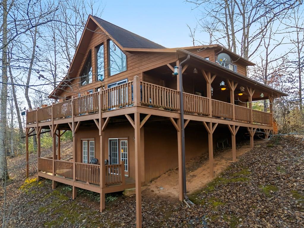 This FULLY FURNISHED two-bedroom, three-bathroom mountain chalet offers a generous floor plan, a finished lower level, and a bonus room, all set on one acre in a quiet, wooded neighborhood with paved roads. A circular gravel driveway provides easy access and ample parking. From the drive, steps lead to a full-length front porch that wraps seamlessly around to an expansive back deck and then to an additional side porch with a ramp leading down into the yard. Inside, the Great Room immediately establishes the chalet's warm character with wood floors, a vaulted ceiling, a dramatic floor-to-ceiling gas-log rock fireplace, and signature chalet windows that frame the seasonal mountain views. Two sets of glass doors open directly to the back deck, creating an easy indoor-outdoor flow. The adjoining kitchen offers lots of cabinet and counter space, an island for extra counter and storage space, matching white appliances, and direct access to the side porch. A short hallway behind the kitchen leads to the laundry area, a spacious guest bedroom with a walk-in closet, and a full guest bathroom. Upstairs, the open loft landing overlooks the Great Room and the MOUNTAIN VIEWS beyond. Through a private doorway, the generous Master Suite features a large walk-in closet and an en suite bathroom. The finished lower level expands the home's livability with a sizable recreation room, its own walk-in closet with built-in shelving, and two sets of glass doors that open to the lower porch. A hallway leads to the bonus room and another full bathroom. With its thoughtful layout, multiple outdoor living areas, and serene natural surroundings, this fully furnished home is move-in ready and waiting for you! Copy this link into your browser to see extra media: https://drive.google.com/drive/folders/1_syJSLV5N0qxwy_ZkMxFd9WLzbU4TRj9?usp=share_link