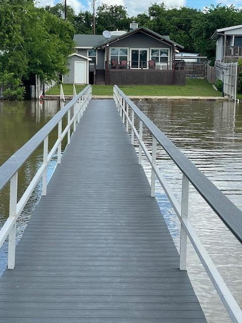 This beautifully remodeled lake house, updated within the past four years, offers modern comfort with scenic lakefront living. The dock has been fully upgraded, featuring a durable metal roof, synthetic decking, and both a boat lift and personal watercraft lift for your convenience. In addition, a professionally installed stone seawall enhances the property's backyard, adding both function and beauty. The expansive covered back deck provides ample space for entertaining family and friends while enjoying lake views. The property is also equipped with a lake pump that supplies water to the sprinkler system, ensuring lush landscaping year-round. While Eagle Mountain's water levels are currently lower than usual, the included photos showcase the lake at its typical levels, offering a true sense of the exceptional views you'll enjoy year-round.