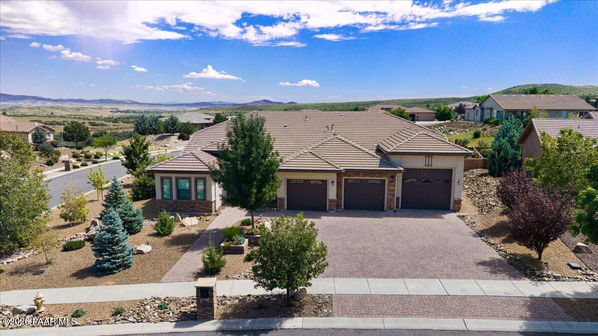 A truly exceptional residence in Stoneridge, this one-of-a-kind home reflects meticulous planning, thoughtful design, and superior craftsmanship throughout.A spacious entry sets an impressive tone, leading to an inviting gourmet kitchen anchored by an oversized island, premium appliances, and elegant floor-to-ceiling finishes. Designed for both effortless entertaining and everyday living, the kitchen is complemented by a beautifully appointed pantry and dedicated office space. The adjacent dining room features custom cabinetry and a granite serving counter, providing additional space for hosting family and friends.The luxurious primary suite offers a spa-inspired bath and an extraordinary walk-in closet, creating a private retreat. Equally well considered, the laundry room includes abundant cabinetry, a farmhouse sink, and a built-in mudroom bench with storage and coat hooks. Every room reveals another refined detail, while the living room frames spectacular views of Mingus Mountain and the surrounding landscape.Outdoor living is equally impressive. An expansive patio, pergola, and hot tub create an exceptional setting for relaxing or entertaining while taking in the panoramic views.For collectors, adventurers, and automotive enthusiasts, the property offers an attached three-car garage plus a remarkable 56-foot-deep RV garage with a 13'2' H x 12' W door. A concealed false-front design opens to accommodate larger RVs while preserving the home's polished exterior. The space provides exceptional flexibility for additional vehicles, recreational equipment, or other pursuits. A folding staircase leads to mezzanine storage, and a workshop at the rear offers further potential, with the option to add insulation and drywall.Rarely does a home combine this level of luxury, functionality, craftsmanship, and breathtaking scenery. This distinctive Stoneridge property is truly in a class of its own.