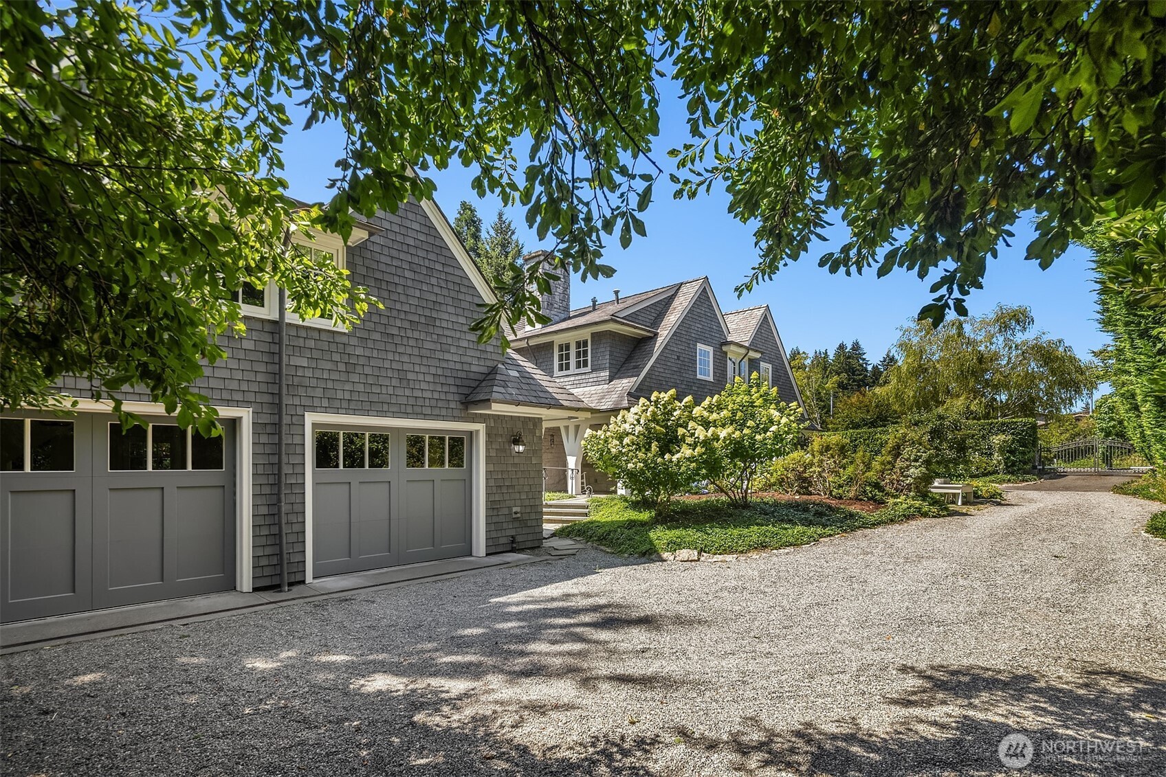 Charming exterior with a gravel drive and lush greenery.