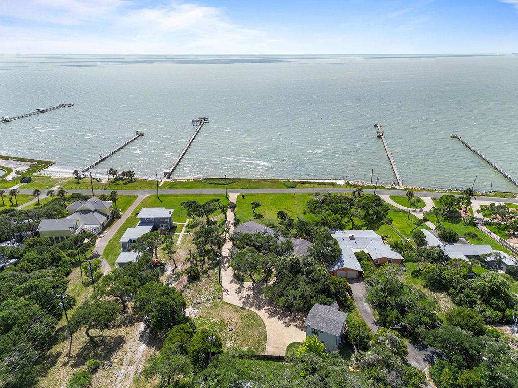 Live Life Well – Waterfront Elegance on Aransas Bay.  Experience refined coastal living at this exceptional 1-acre waterfront estate, where panoramic Aransas Bay views and timeless elegance define every detail. Tucked beneath the sweeping branches of mature live oaks, this private retreat offers a rare blend of sophistication, serenity, and space. The main residence features four generously sized bedrooms, each designed to showcase the stunning bayfront scenery or famous windswept live oaks. Thoughtfully crafted for comfort and entertaining, the home's layout invites effortless indoor-outdoor living. A beautifully appointed detached guest house with a kitchenette provides elegant accommodations for visiting guests, while a separate caretaker's apartment above the two-car garage ensures seamless estate management or additional guest space. Whether you're enjoying sunrise views from the porch or hosting evening gatherings under the stars, this waterfront sanctuary offers a lifestyle of grace and ease. Luxury, privacy, and tranquility—live life well on Aransas Bay.