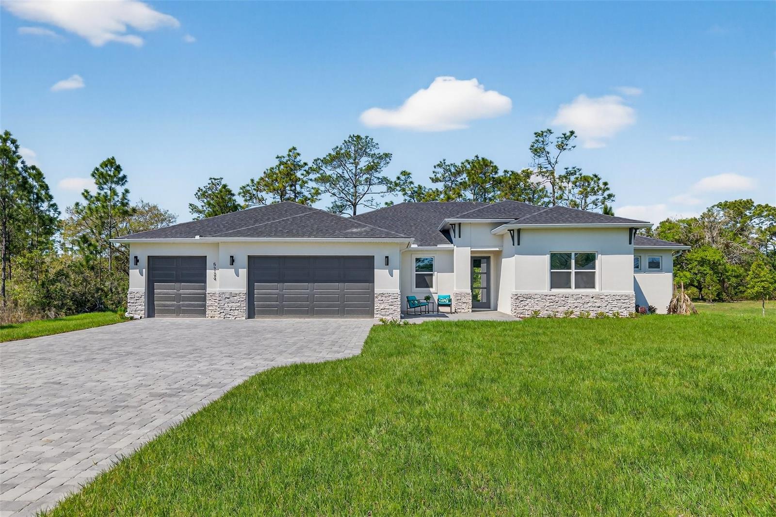 Experience refined design and thoughtful craftsmanship in this brand-new modern residence, set on a full 1-acre lot with NO WETLANDS -offering the flexibility to add a pool, fence, workshop, or ADU without wetland restrictions or delineation.From the moment you enter, the open-concept floorplan is filled with natural light and designed for connection. The expansive living room flows seamlessly into a large formal dining area and a stunning designer kitchen, ideal for both entertaining and everyday living. The kitchen will feature 42” solid wood cabinetry, quartz countertops with a dramatic waterfall island, tile backsplash, a  built-in wall oven, glass cooktop, pendant lighting, and a spacious pantry. A striking accent slat-wood wall on the back of the island adds warmth and architectural interest. Custom cabinet organizers are thoughtfully installed in the pantry, laundry room, primary bedroom closet, and secondary primary bedroom.Sliding glass doors lead to a covered pavered, lanai, pre-plumbed for an outdoor kitchen, where you can unwind and take in gorgeous sunset views over the peaceful backyard. The open layout is enhanced by 8-foot doors and sliders, creating an airy, upscale feel throughout the home.This home offers two primary bedrooms, providing flexibility for guests or multi-generational living. The main primary suite is a private retreat featuring a spacious seating area and its own entrance to the lanai, along with a spa-style bath complete with a double quartz vanity and a walk-in shower finished with tile extending to the ceiling. The second primary bedroom includes its own private bathroom, while the additional bedrooms are generously sized and share a well-designed bath.A private office offers a quiet workspace, while the very large secondary bedrooms ensure comfort for everyone. Additional features include tile flooring throughout, black matte hardware, energy-efficient insulation, LED lighting, Energy Star® appliances, gutters, and an irrigation system.Car enthusiasts and hobbyists will appreciate the four-car garage with oversized 8-foot garage doors, along with an extended 100' paver driveway.  The front paver patio is perfect for enjoying rocket launch views right from your front door!Located in a quiet neighborhood that feels private without being secluded, this home is conveniently situated within approximately 30 minutes of everything Central Florida has to offer, including beaches, downtown Orlando, Orlando International Airport, and world-renowned theme parks. Builder warranty included for added peace of mind.A rare opportunity to enjoy modern luxury, usable land, and an exceptional lifestyle, all in one thoughtfully designed home.