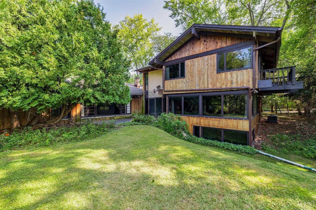 A once-in-a-generation Freeland estate brimming with character and heart: over 8,368 sq. ft. of living space on 5.55 magical acres, graced by mature apple and pear trees that whisper the history of the Bintz family-creators of "Bintz Apple Mountain Resort". The property consists of two separate parcels being sold together: 28-12-3-03-3010-002 (2.17 acres with the residence) and 28-12-3-03-3010-001 (3.38 acres of back yard, creek, fire pit, and 20+ fruit trees). The home is tucked back on a winding drive, surrounded by trees for peace and privacy. While it backs to the serene 10th fairway and 11th green of Apple Mountain Golf Course, a tall wooden fence ensures complete seclusion from the course and public. Step inside to a dramatic foyer entry leading into a great room lined with floor-to-ceiling windows and Douglas Fir exposed beams that crown soaring wood ceilings and frame sweeping wooded views. Gathering spaces are both impressively large and warmly quaint. The well-appointed kitchen sits between the formal living room and a huge eating area, perfect for entertaining or everyday living. Custom made one- of-a-kind lighting fixtures throughout the house and pool room adds to the artistic flair and unique ambiance throughout. The main floor offers two bedrooms with a full bath, while a grand stairway leads to the expansive primary suite retreat. The main floor library offers a fireplace and built-in bookshelves. A full basement bedroom provides even more living space, and a 3-car garage plus whole-house Generac generator and partial home air conditioning add practicality to the home's character. The dramatic indoor pool room/wing features rich brick flooring and walls, a shimmering 20'—40' (11' deep end, w/diving board) Beattie pool, and its own shower, bath, changing room, and laundry - ideal for year-round enjoyment. Outdoors, mornings begin with soft light through the trees, afternoons glow in dappled shade, and sunsets and evenings sparkle with fireflies in the orchard. Despite its private wooded setting, t
