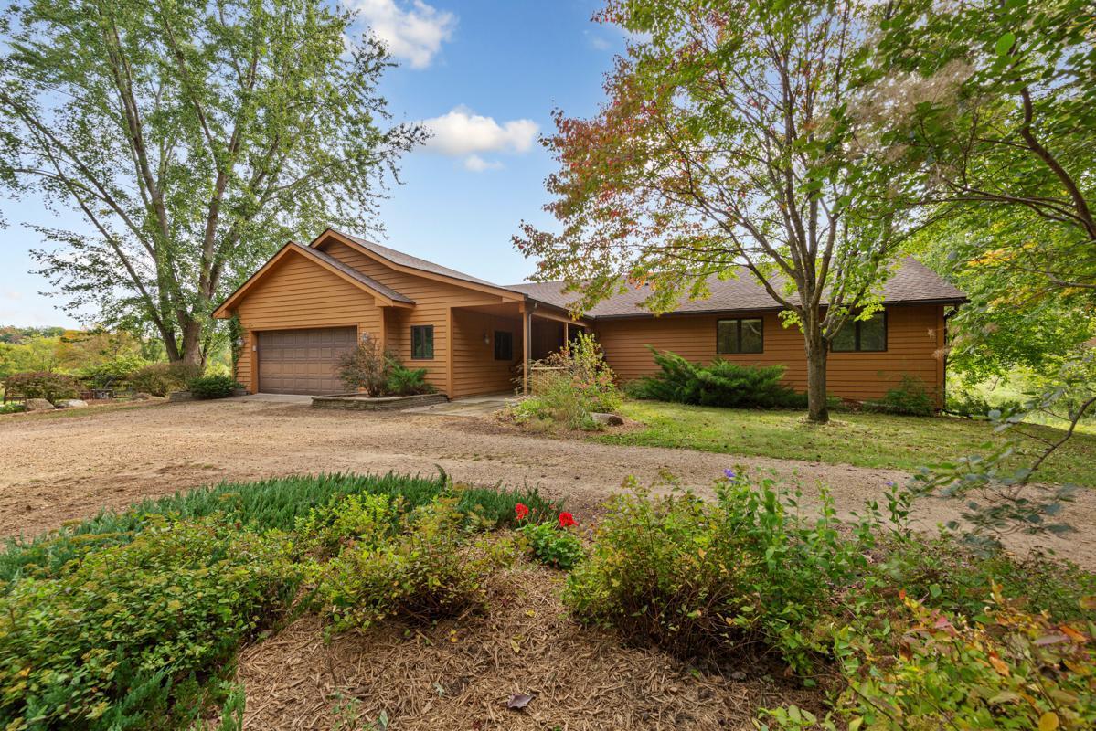 Country Estate on 37+ Acres. Experience the serenity of wide-open spaces on this 37+ acre property with a wraparound deck overlooking acres of fields, rolling hills and pasture ground. It’s more than just land—it’s a retreat, a reset, plenty of space for loved ones to gather. It gives privacy, it isn’t just place isn’t a place to live, it's your own little piece of paradise. The entryway to the home opens to a bright, sunlit interior. From the oversized garage, featuring in-floor heat, is a large mudroom and powder room, ideal for cleaning up after a day outdoors. Steps inside the Living Room with in-floor heat, soaring wall to wall windows and cozy Fireplace create the ultimate lodge style gathering space. The Kitchen is designed for both beauty and function, featuring quartz countertops, a spacious island, a built-in buffet, plenty of custom cabinet space to keep everything organized, while the open layout flows seamlessly into the dining room and living room. The main level offers two spacious bedrooms, a full bathroom, and a versatile private office or den.  Lower level: In addition to the third bedroom, you'll love the newly updated flooring, additional gas stove, look out windows and third bathroom- perfect for a cozy guest space or recreational area.  Exterior and Land: Pole shed and partial fencing- ideal for horses, hobby farming or heavy equipment storage. 37+ Acres of open land and mature trees perfect for exploring, livestock, hunting or simply soaking in the view. This home offers the rare combination of rustic outdoor charm and modern upgrades, giving you the perfect Yellowstone-inspired escape without leaving home. The township is well-connected by roads; Interstate 35 and State Highway 19 run through it for easy commuting.