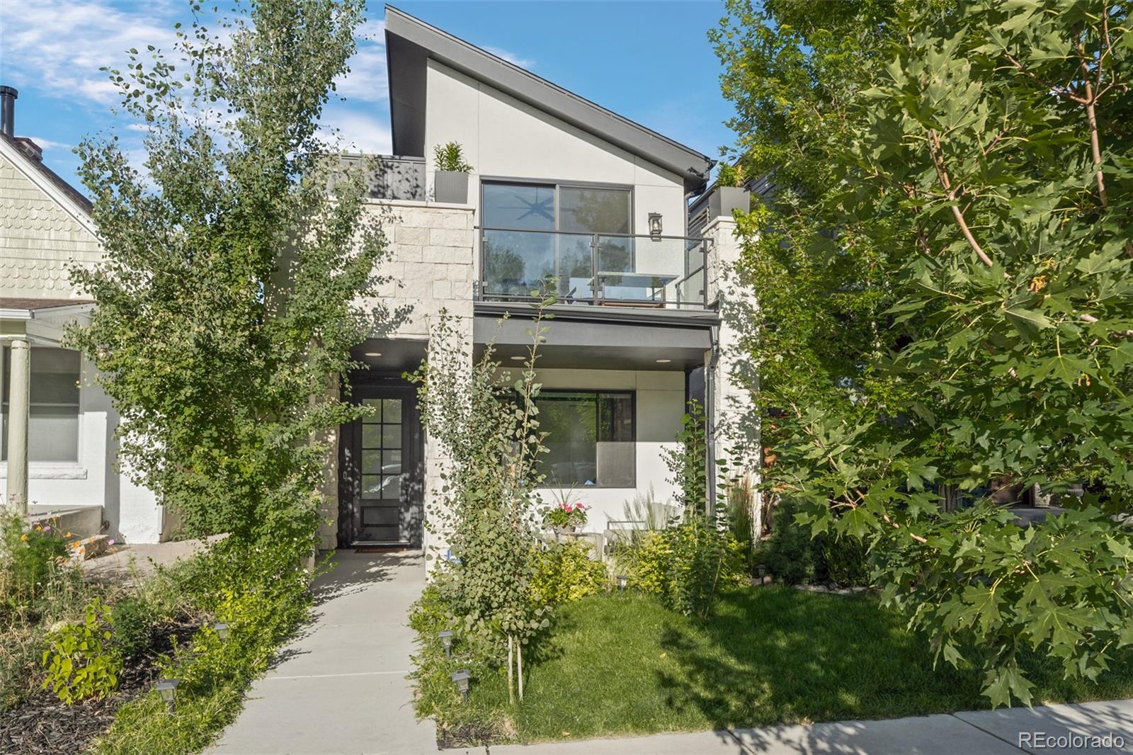 Tucked into one of Denver's most coveted neighborhoods, this home is a rare retreat that blends privacy, sophistication, and accessibility. Built in 2020, this 5-bedroom, 4-bathroom home spans more than 3,200 square feet of refined living space, offering both tranquility and the vibrancy of LoHi just beyond the front door. The main floor showcases an ideal layout with effortless flow between living, dining, and entertaining spaces. At its center, a chef's kitchen boasts an oversized quartz island, professional-grade appliances, and designer lighting. The living room, anchored by a sleek gas fireplace, opens through sliding glass doors to a lush backyard with mature trees, water feature, and stone patio -- perfect for quiet evenings or lively gatherings. A main-level bedroom or office with full bath provides flexibility. Upstairs, the primary suite is a private sanctuary, complete with vaulted ceilings, a sunlit terrace amongst the trees, and spa-inspired bath featuring dual vanities, soaking tub, and walk-in shower. A boutique-style custom closet elevates the retreat, while two additional bedrooms, a full bath, and laundry complete the upper level. The expansive rooftop deck redefines outdoor entertaining with a kitchenette, 6-burner gas grill, hot tub, and over 800 sq ft of space. Dine under custom shade sails, watch the city lights from the lounge and fire pit, or unwind in the hot tub with sweeping Denver skyline views. The finished basement extends the lifestyle experience with a theater, rec room, full bathroom, and bedroom -- currently curated as a fitness space. Detached two-car garage w/ the roof of the garage featuring a 6.2kW solar system that is fully owned and saves drastically on energy costs. Balancing serenity with city living, this Highlands residence is a lush, private oasis just minutes from Denver's acclaimed dining, shopping, and nightlife.