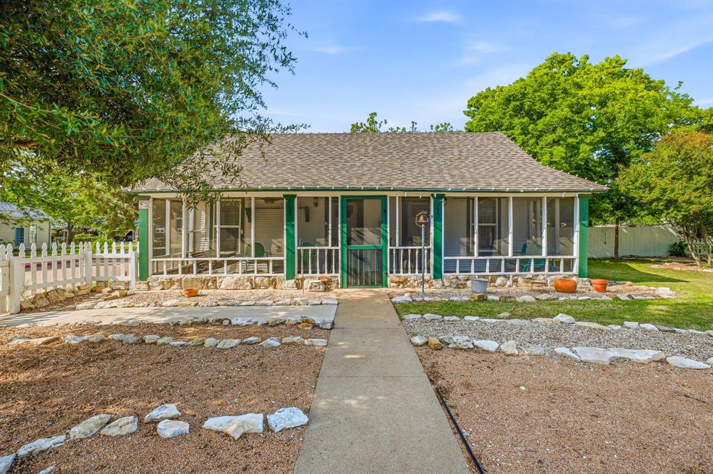 Built in 1877 and thoughtfully restored, this historic Granbury cottage offers a rare opportunity to own a true piece of Hood County history just moments from the Historic Downtown Square. Situated on a full lot in the desirable Historic District, this 2-bedroom, 1-bath home blends original character with functional updates for modern living.From the inviting screened-in front porch to the preserved interior details, the home reflects the craftsmanship and charm of its era. Inside, you’ll find warm wood accents, a comfortable layout, and natural flow between the living, dining, and kitchen spaces. The bedrooms are privately positioned, making the home both practical and welcoming.The outdoor space is designed for both enjoyment and ease, featuring mature trees, established landscaping, and multiple areas to relax or entertain. The full lot provides added space and flexibility that is hard to find this close to the Square.A standout feature of the property is the detached carriage house, offering additional potential for storage, workshop space, or future improvement. Opportunities like this—combining historic character, a full lot, and proximity to Granbury’s most sought-after destination—are rare.Whether you’re looking for a primary residence, weekend retreat, or investment opportunity, this property delivers location, charm, and upside.
