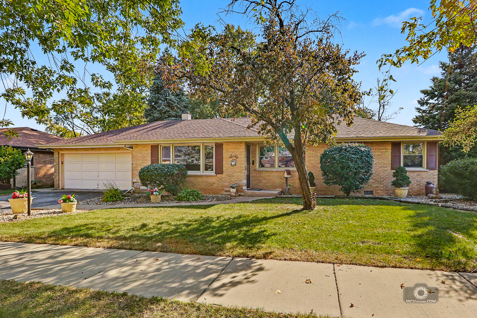 Welcome to this solid, all-brick ranch nestled at the end of a beautiful, tree-lined street! Step inside to discover a spacious living room filled with natural light pouring through a large picture window. Centrally located, the kitchen features oak cabinetry and a generous eating area that opens to both the front living room and the inviting family room at the back of the home. Here, you'll find a cozy corner fireplace and sliding glass doors leading to the outdoor patio, creating the perfect setting for relaxing or entertaining. A separate laundry room adds convenience to your everyday routine. All three bedrooms feature exposed hardwood flooring, which also extends beneath the living room carpeting. The spacious hallway bathroom offers dual sinks and a linen closet, while a second full bathroom is conveniently located off the family room. You'll also appreciate the oversized attached 2.5-car garage, providing plenty of room for parking and additional storage. Additional highlights include a roof replaced just two years ago and replacement windows throughout most of the home, with the exception of the back family room. Outside, the spacious backyard offers endless possibilities for outdoor enjoyment, gardening, entertaining, or simply unwinding in your own private retreat. Offering solid construction, comfortable living spaces, and plenty of potential to make it your own, this home is a wonderful opportunity to create something special. Don't miss your chance to make this charming ranch your own!