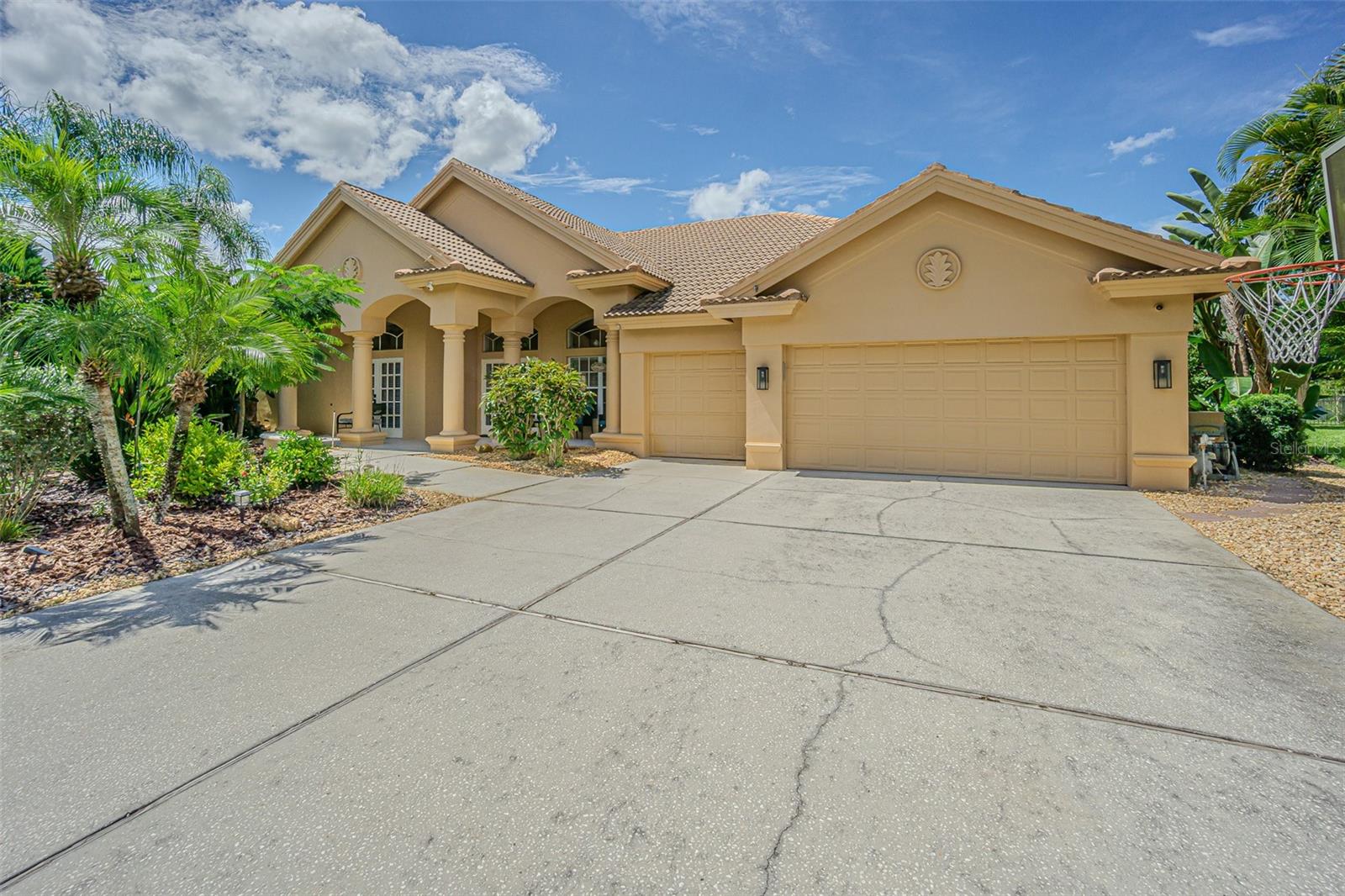 Nestled on the shores of Lake Tarpon in the desirable community of Juniper Bay, this exquisite residence offers the perfect balance of privacy, natural beauty, and refined living. Situated on a premium .72-acre pond and conservation lot at the end of a quiet cul-de-sac, the property provides serene surroundings with no rear neighbors. From nearly every room, enjoy sweeping views of the pool, mature gardens, and conservation area, where deer and a variety of birds are daily visitors. This thoughtfully designed 5-bedroom, 3-bath, 3-car garage home features a versatile triple split floor plan that ensures both privacy and functionality. As you enter through the elegant glass double doors, you are welcomed into a formal living and dining area with soaring ceilings adorned with crown molding. Ceramic tile flooring flows throughout the main living areas, adding both style and durability. The primary suite is a true retreat, complete with tray ceilings, crown molding, dual vanities, a soaking tub, a private water closet, and two walk-in closets for unparalleled storage. Adjacent to the suite, the fifth bedroom—perfect as an office—features double doors, Brazilian oak flooring, and its own closet.  Two guest bedrooms are generously sized and include charming window seats. The back bedroom doubles as a private en-suite when paired with the pool bath.  At the heart of the home, the gourmet kitchen boasts white cabinetry, double ovens, granite countertops, 42-inch upper cabinets with crown molding and under-cabinet lighting, a decorative tile backsplash, stainless steel appliances, and an extended island ideal for entertaining. The adjoining family room offers warmth and character with its natural wood-burning fireplace framed by coral surround and built-in shelving. Step outside to your own private oasis. The spectacular pool area with a sheer descent waterfall creates a tranquil backdrop for relaxation, while the expansive deck provides plenty of space for outdoor dining and entertaining. A fenced yard adds security and peace of mind for pets and family.  Additional highlights include: Abundant natural light through extensive windows and French doors, laundry room with built-in cabinetry and utility sink, and expansive pool and conservation views from nearly every living space. As part of the Lansbrook community, residents enjoy exclusive access to Lake Tarpon via a fishing pier and boat ramp, as well as two parks with playgrounds, basketball, pickleball, and a party pavilion. The community also offers a golf course, and direct access to the Pinellas Trail for walking, jogging, and biking. Top-rated schools add to the appeal of this highly desirable location. This exceptional home offers not only a stunning property but also a lifestyle defined by nature, recreation, and convenience.