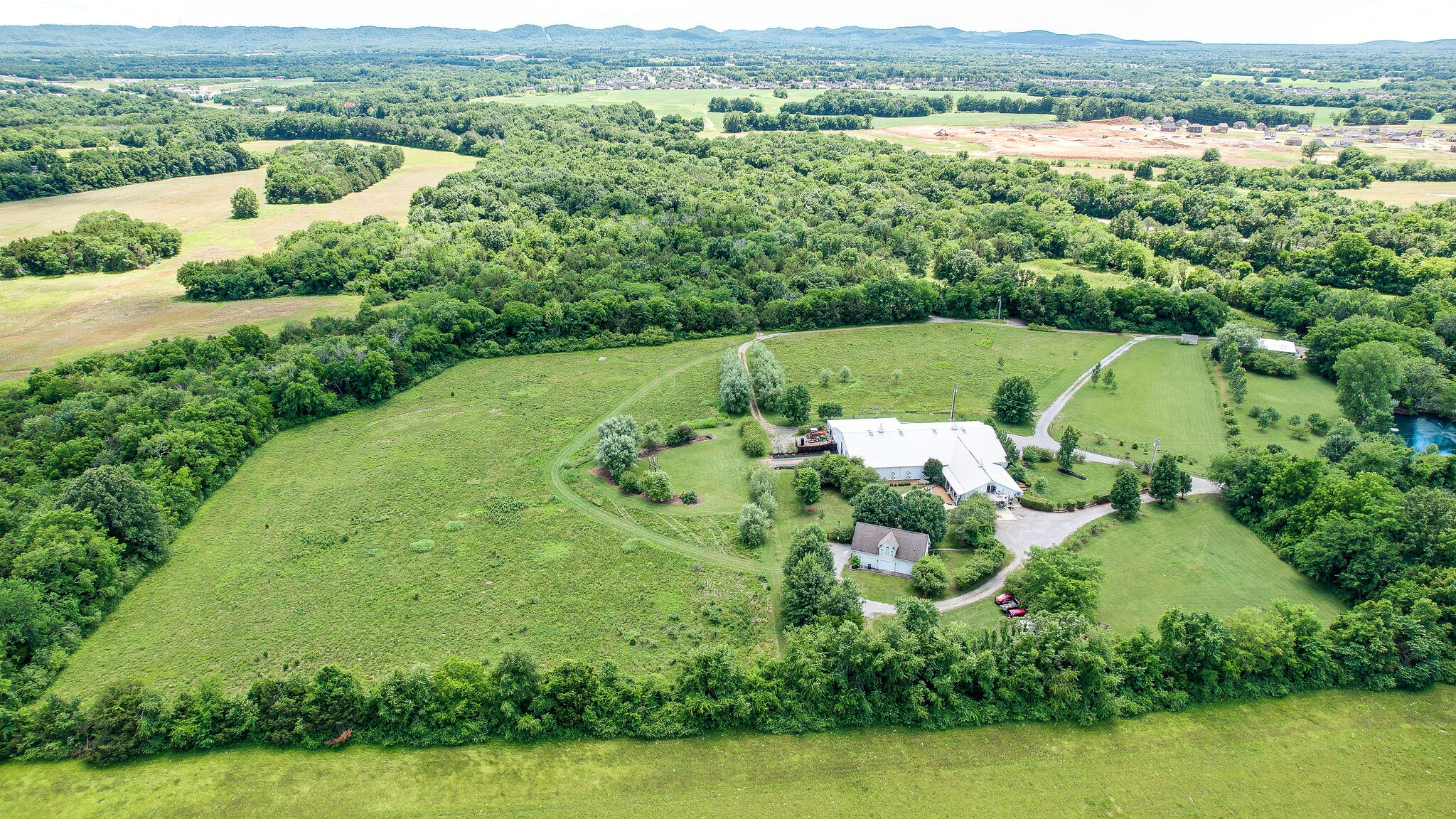 Discover a rare opportunity to own 53+/- acres in Middle Tennessee offering the perfect balance of privacy, seclusion, and convenience for a private estate, family compound, equestrian property, or possibly a wedding and event venue. Tucked behind a gated entrance and surrounded by a peaceful rural setting, this exceptional property provides the space to create a truly remarkable destination while remaining just minutes from Murfreesboro. Whether your vision includes a private estate, multi-generational family compound, equestrian retreat, or a wedding and event venue, this versatile property offers the acreage, privacy, and natural beauty to bring your plans to life. Multiple additional homesites with preliminary soils approval for septic, provide opportunities for a family compound options or additional guest accommodations, while the scenic landscape creates an inviting backdrop for recreational enjoyment, or even the possibility of a wedding and event center.The property's secluded atmosphere offers a sense of escape rarely found this close to town, with convenient access to shopping, dining, medical services, and major transportation corridors. Mature trees, and open spaces, combine to create an exceptional setting where privacy and accessibility come together in one outstanding offering. Properties of this size and location are increasingly difficult to find. Whether you're seeking a legacy family property, a premier estate setting, or a unique commercial opportunity, this 53+/- acre tract presents unlimited potential in one of Middle Tennessee's most desirable growth corridors. The improvements include the following: Metal Barn - approximate 8,000 sq. ft. with concrete floor plus stalls including dutch doors overlooking the pasture. Main House - approximate 2,400 sq. ft. newly updated throughout with 3 bedrooms, and 2 baths on the main level, along with a studio apartment layout on the upper level. Guesthouse open lower level with upper studio apartment