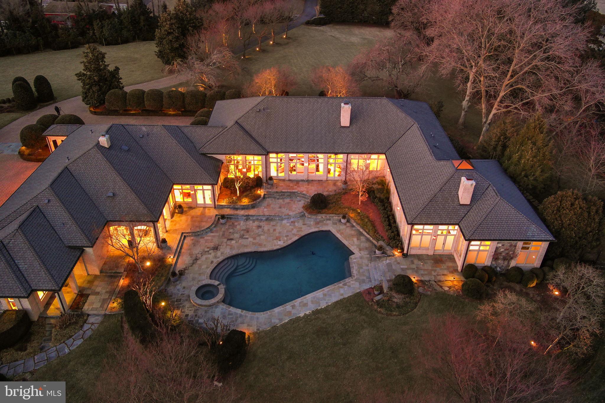 Luxury Oasis in Great Falls – A Private 5-Acre EstateTucked away on a private road off Georgetown Pike, this stunning 5-acre estate offers an unparalleled blend of elegance, comfort, and resort-style living. Boasting nearly 9,000 square feet on the Main Level, and 13000 square feet under roof for the ultimate in single-level living. This custom-built home is a masterpiece of design, featuring the highest quality materials, exquisite craftsmanship, and over $1 million in breathtaking landscaping.Sophisticated Interior & Grand Living SpacesAs you step through the grand mahogany double doors, a magnificent reception hall with hardwood floors and custom moldings welcomes you. The sunken formal living room, with a striking masonry fireplace and expansive views of the pool, creates a warm and inviting atmosphere. Adjacent, the formal dining room also overlooks the outdoor oasis, setting the stage for elegant gatherings.The chef’s kitchen is a culinary dream, featuring two center islands—one for cooking and another for prep—top-of-the-line appliances, industrial-strength gas cooking, a Sub-Zero refrigerator, black galaxy countertops, and custom flat paneled cherry cabinetry. A spacious Costco pantry, powder room, and garage entry foyer provide additional convenience. The open-concept breakfast area, with walls of glass, seamlessly flows into the family room, which showcases a stunning stone fireplace, custom built-ins, and recessed lighting throughout. Just outside, an outdoor kitchen and private poolside bathroom, featuring a private spa with a sauna, shower. All this elevates the outdoor entertaining experience.Private Office Wing & Luxurious BedroomsA dedicated office wing offers two private offices—ideal for working from home—along with an additional formal powder room. The bedroom wing features five oversized bedrooms, each with en-suite bathrooms, walk-in closets, and recessed lighting.The primary suite is a sanctuary of relaxation, with a private sitting area, dual-sided fireplace, and direct access to the patio and pool. The spa-like primary bath boasts dual vanities, a soaking tub, an expansive custom closet, and a luxurious shower with multiple showerheads and body sprayers.Incredible Lower Level & Guest HouseThe lower level is designed for ultimate entertainment, featuring a stylish sitting area, billiards room, game room, and a custom bar with pendant lighting and natural cherry cabinets as well as black galaxy countertops. Dual pocket doors lead to a state-of-the-art media room with seating for ten. Additional highlights include a spacious exercise room and a powder room.A separate guest house offers a private retreat with a bedroom, living room, small full kitchen, and bathroom. The quest has its own entrance—ideal for extended stays or an au pair or in law suite.Resort-Style Outdoor LivingThis estate’s outdoor spaces are truly spectacular. A heated inground pool serves as the focal point, visible from most rooms in the home. Lush landscaping, with up-lighting on mature trees, creates a serene ambiance. A sports court, hidden within the landscape, offers the perfect space for basketball enthusiasts. A screened porch overlooks the expansive backyard, providing an additional space to unwind.The five-car garage is a car collector’s dream, complete with heat and a unique drainage system. The paver driveway, with a front parking area and motor court, enhances the estate’s grand entrance.An Unparalleled OfferingThis extraordinary Great Falls estate offers privacy, luxury, and every imaginable amenity. A true oasis, just minutes from the heart of Great Falls and major commuter routes, yet worlds away in tranquility.Schedule your private tour today and experience the unmatched beauty of this remarkable home.