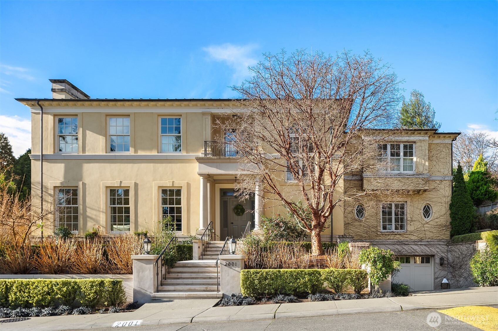 Inspired by Georgian architecture originating in England, this Broadmoor Estate was designed by Stuart Silk and built to the highest standards by Toth Construction. The lush and private gated grounds were designed by Williamson Landscape Architecture and include a second buildable tax parcel with flexible open space and extensive gardens. The designer interiors blend modern living with elegant trim details and luxury finishes. Greet your guests in the large entry hall and enjoy a circular layout featuring formal living, dining, a grand wood-paneled office, a chef’s kitchen, and a great room, all with 10-foot ceilings and effortless access to the backyard. A dramatic spiral staircase leads to four en-suite bedrooms that anchor the upper level, plus a large laundry room and partial golf course views. The lower level features a paneled rec room with theater and billiards, a wine cellar, a fitness studio, and guest quarters with a separate entrance, kitchen, and private courtyard. Elevator access to all three levels and a four-car garage complete this distinguished offering, located in Seattle's only gated community.