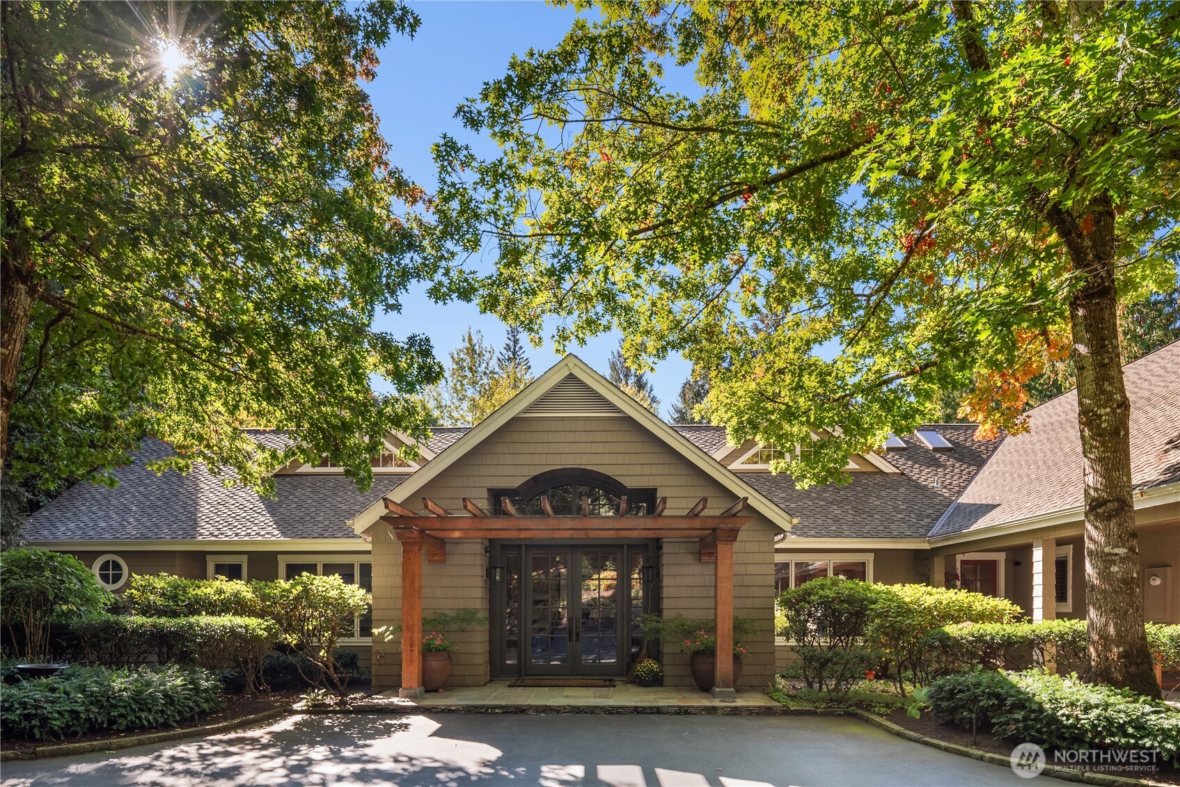 Front entry with timber pergola and glass double doors shaded under trees