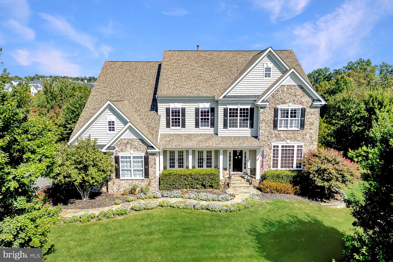 An exceptional opportunity to own one of the finest homes currently available in The Park at Belle Terra. This impressive executive residence offers more than 5,700 square feet of beautifully appointed living space with five bedrooms and four and a half bathrooms, all set on a picturesque ¾ acre lot backing to community open space with scenic views.The home immediately impresses with striking curb appeal including a stone front exterior, landscaped walkway, welcoming covered porch, and a side-load three-car garage. Inside, the grand two-story foyer showcases elegant trim work, decorative columns, neutral tones, and a sweeping curved staircase. Rich wood flooring enhances much of the main level, creating a warm and refined setting.The thoughtfully designed main level offers a balance of elegance and functionality with a formal dining room featuring a tray ceiling and detailed moldings, a bright living room with French doors that open to the front porch, and a private study with custom built-ins and glass French doors. The inviting family room includes plush carpeting, a gas fireplace, and access to the screened porch, providing a comfortable space for gathering and relaxation.The gourmet kitchen is designed to impress with high-end appliances, quartz countertops, subway tile backsplash, a large center island with pendant lighting, and abundant workspace and cabinetry. A sun-filled breakfast area leads directly to the rear deck, making indoor and outdoor entertaining effortless.Upstairs, the expansive primary suite offers a peaceful retreat with large windows, a spacious sitting area, and a convenient bar with mini refrigerator. The luxurious bathroom features a soaking tub, walk-in shower, and dual walk-in closets with custom storage solutions. Additional bedrooms are generously sized with plush carpeting and walk-in closets. One bedroom includes a private ensuite bath, while two others share a well-designed Jack and Jill bathroom. A convenient upper-level laundry room with utility sink adds everyday practicality.The walk-out lower level includes a private au pair or in-law suite complete with a bedroom and full bathroom, along with ample unfinished space ready to be customized to suit future needs.Outdoor living spaces make this property truly special. The cathedral ceiling screened porch features surround sound and ceiling fans, while the large deck overlooks a fenced backyard ideal for entertaining or relaxing. The patio includes a fully equipped outdoor kitchen with built-in grill, exterior refrigerator, and a stone bar, creating a perfect setting for gatherings or quiet evenings outdoors.This remarkable property combines space, elegance, and a beautiful natural setting within one of the area’s most desirable communities.