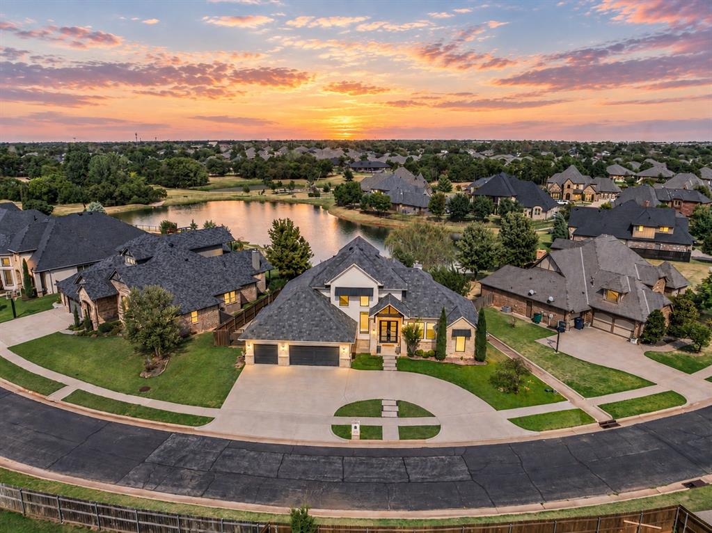 WOW—waterfront living has never looked so good! Welcome to 15400 Kestral Park Court in The Lakes at Traditions, where spectacular pond views, grand living spaces, and exceptional outdoor living create a home designed to impress. From the moment you enter, soaring ceilings and expansive living areas set the tone. The main living room is filled with natural light and features impressive sliding doors that open to the covered patio, beautifully connecting the indoors with the waterfront setting beyond. Two dining areas provide wonderful versatility for elegant entertaining or casual everyday living. The kitchen commands attention with a large center island, abundant cabinetry extending to the ceiling with beautiful lighting, and an open design that keeps everyone connected. Retreat to the private primary suite featuring its own patio access and a spa-inspired bathroom with a floating vanity, dramatic floor-to-ceiling dressing mirror, and an exceptionally designed closet with thoughtful organization throughout. A downstairs ensuite provides privacy and flexibility for guests. Upstairs, discover an incredible media room or 4th bedroom complete with a balcony showcasing gorgeous views of the community pond—the perfect place to unwind and take in the scenery. The utility room adds function with a sink and mud bench. Outside is where this home becomes unforgettable. The expansive covered patio features a vaulted ceiling and outdoor fireplace, creating a spectacular year-round entertaining space overlooking the water. The oversized backyard offers plenty of room for a future pool and additional outdoor amenities. The Lakes at Traditions offers gated entry, clubhouse with fitness center, neighborhood pool, playground, dog park, and stocked ponds. Located within Edmond Schools with convenient access to the Kilpatrick Turnpike, Broadway Extension, and I-35. Luxury, lifestyle, and a view you will never tire of—this is waterfront living at its finest. Welcome Home!